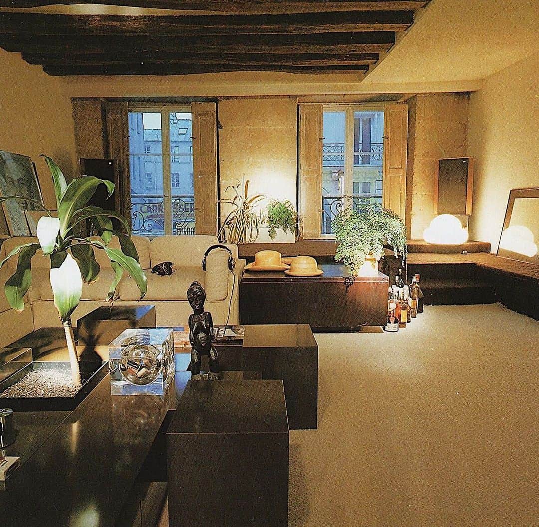 Meganのインスタグラム：「Rooms by Design, 1989 ⚡️ . . . . #theworldofinteriors #interiordesign #indoorplants #maidenhairfern   Interior designer Marc Lornat stripped two centuries’ worth of “improvements” from his Paris apartment - originally a mid-eighteenth-century carriage house. Here, hand-hewn beams and stone window piers endow the living room with a feeling of history. Behind the seating corner, a raised platform, carpeted in dark brown, comes into its own for small dinners - or gregarious buffets.」