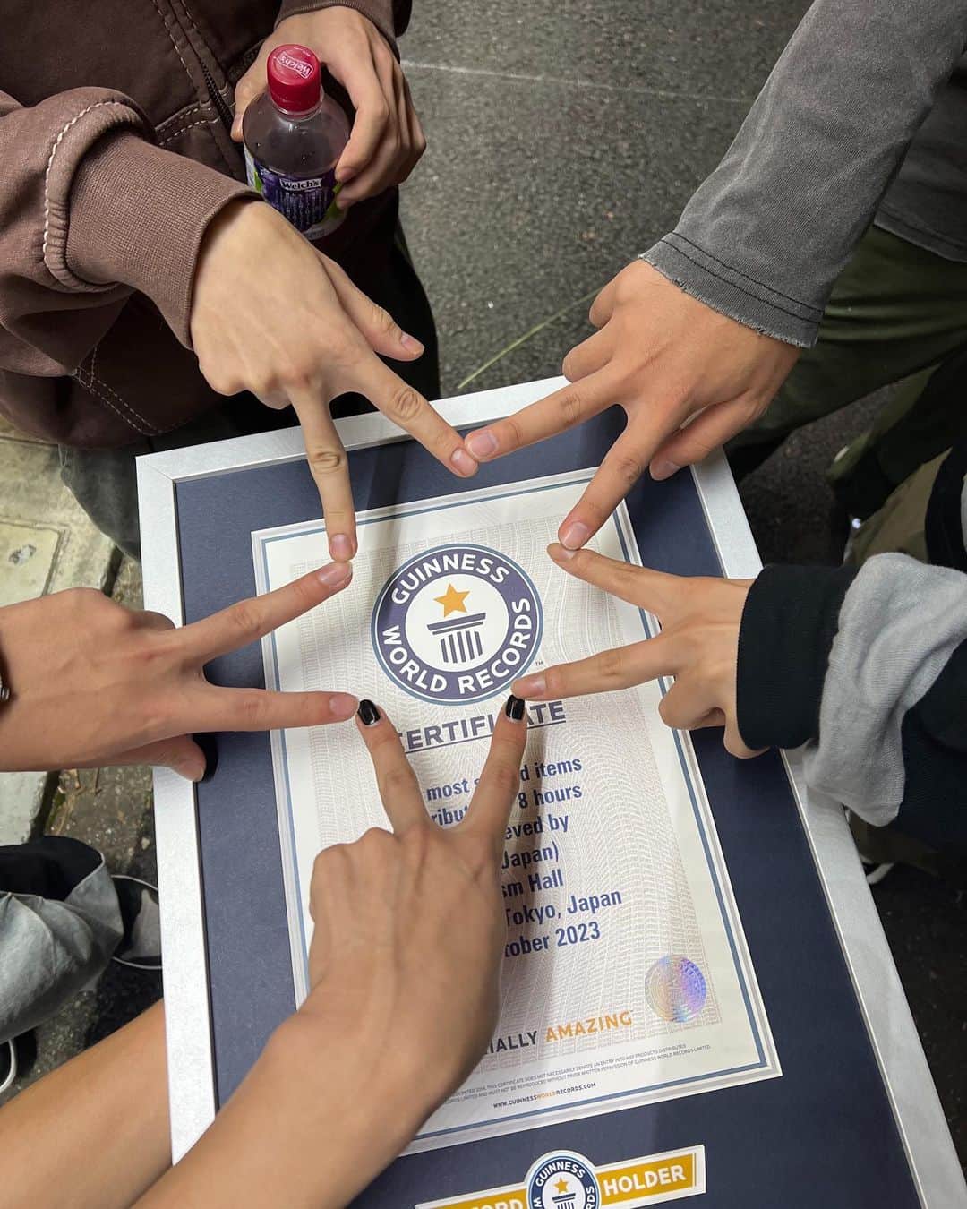 のインスタグラム：「ギネス世界記録🥇  コムドット結成5周年である10/1にギネス世界記録に挑戦しました。元々この挑戦はコムドット卓上カレンダー2024を発売するにあたり何かイベントをしたいと考えていたところ、編集担当の小寺さんから「ギネス世界記録挑戦します？」と訊かれ二つ返事で「それおもろいっすね」と言ったところから始まりました。 今回挑戦したギネス世界記録は"8時間で最も多く配布されたサイン入りアイテムの数"です。文字通り達成するには複数の条件をクリアしなければならない記録です。特にコムドット5人だけでは絶対に達成できないファンの人と力を合わせて挑む必要がありました。当たり前のように「ファン10000人にカレンダー手渡しします」と動画で宣言しましたが、よくよく考えたら10000人がわざわざ会いに来てくれるということの凄さ、価値は簡単に形容できません。当日「仕事休んできました」「インドネシアから帰国しました」「娘のために1人できました」「ディズニーから抜けてきました」「5周年お祝いにきました」とファンの方一人一人と目を合わせて言葉を受け取り、みんなの時間をもらってこの記録に挑んでいることに改めて気付かされました。カレンダーを受け取る3秒のために予定を空けてくれたり、ネイルや髪型を変えてくれたり、言うことを考えたり、ワクワクしてくれたことを想像していかに今自分たちが幸せなのかを思い知りました。改めて会いにきてくれた10000人の皆さん本当に本当にありがとうございました。5周年の節目にファンのみんなとギネス世界記録に挑戦できたこと一生の思い出になりました。 直接応援されることがどれだけ勇気と元気がもらえて、コムドットメンバー5人にとって励みになっているか計り知れません。こんなふうに自分たちが支えられているんだと実感する本当にいい機会になったので、応援してくれるみんなに胸を張れるようこれからもまっすぐ活動していきたいと思います。そして今回予定があったり、体調を崩しちゃったり、当選せずに会いに来れなかったみんなの気持ちもしっかり届いています。また会える機会を必ず作るのでその時は絶対に会おうね。 5周年のお祝いも精一杯受け取ってパワーもらったのでここからは心機一転6年目頑張っていこうと思います。これからもコムドットのことをよろしくお願いします❤️‍🔥  Big respect: @tomoko_kodera」