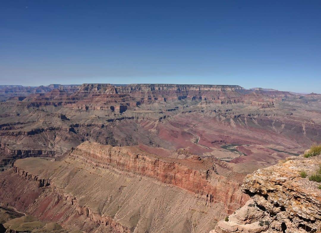 山賀琴子さんのインスタグラム写真 - (山賀琴子Instagram)「アメリカ旅行記② Grand Canyon  地球46億年の歴史のうちその約半分の20億年分の地層が見える世界道産、グランドキャニオン！全長450km 深さ1.6kmと圧巻のスケール！ ナナは2回目、はんにゃと私は初めての場所。 いや〜、、、圧巻。すごい。自然ってすごい！ これは世界七不思議になるわけだよ。 グランドキャニオンがどうやってできたか、未だにはっきりとは分かっていないってところもロマンがあるよね🌏 自然には計り知れない力があるんだなぁと思い知らされた。 野生動物も結構いるとガイドさんが説明をしてくれた矢先、大きな鹿が道沿いにいたり、見れたらラッキーと言われているらしい青い鳥が目の前を飛んで行って、ハッピーラッキーでした✨  そしてグランドキャニオンの前に寄ったダイナソートラックも楽しかった！一見何もない土地で、地面をよく見ると沢山恐竜の足跡が！！ ナバホ族の方が言うには、緑色の石のようなものは恐竜のうんちの化石らしい🦕大きい足跡の横に小さい足跡があって、これは間違いなく恐竜の足跡だ。なんか可愛い。  地球の歴史と、アメリカの広さをひしひしと感じることができました🌏  One of the seven wonders of the world, where you can see 2 billion years of strata. I was overwhelmed by the magnificent nature. I was so lucky to see a blue bird🕊️💙」10月7日 16時19分 - kotokoyamaga