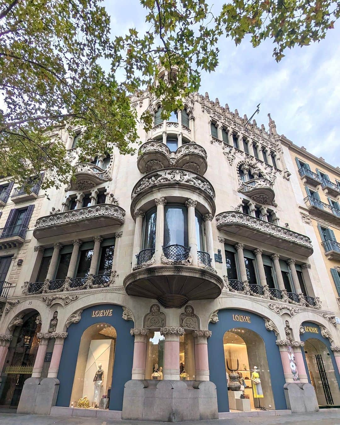 安岡あゆみのインスタグラム：「. Passeig de Gràcia🇪🇸 独特な20世紀建築物と高級ブランド店が立ち並ぶグラシア通り。 . 世界遺産に登録されている「カサ・ミラ（Casa Milla）」と「カサ・バトリョ（Casa Batllo）」はアントニ・ガウディの代表的な作品。 モデルニスモ様式という曲線が特徴で、植物をはじめとした自然界をモチーフとし、曲独創的で芸術的なデザインです。 . 花模様を巧みに表現したことから「花の建築家」と呼ばれ、生前はガウディ以上に名声を博したモンタネールにより改装された「カサ・リェオ・イ・モレラ」。 1階にはスペイン王室御用達の高級ブランド「ロエベ LOEWE」が入っています。 ブランドブティックの中でも一際目立っていました。 . グラシア通りは日本で言うと、銀座のような雰囲気かな🛍️ . . #barcelona #spain #barcelonatravel #spaintravel #passeigdegracia #casamila #casabatllo #antonigaudi #montaner #ayumi_y_travel #バルセロナ #スペイン #グラシア通り #アントニガウディ #カサミラ #カサバトリョ #モンタネール #ロエベ #バルセロナ旅行 #スペイン旅行 #ヨーロッパ旅行 #ヨーロッパ周遊 #世界遺産」