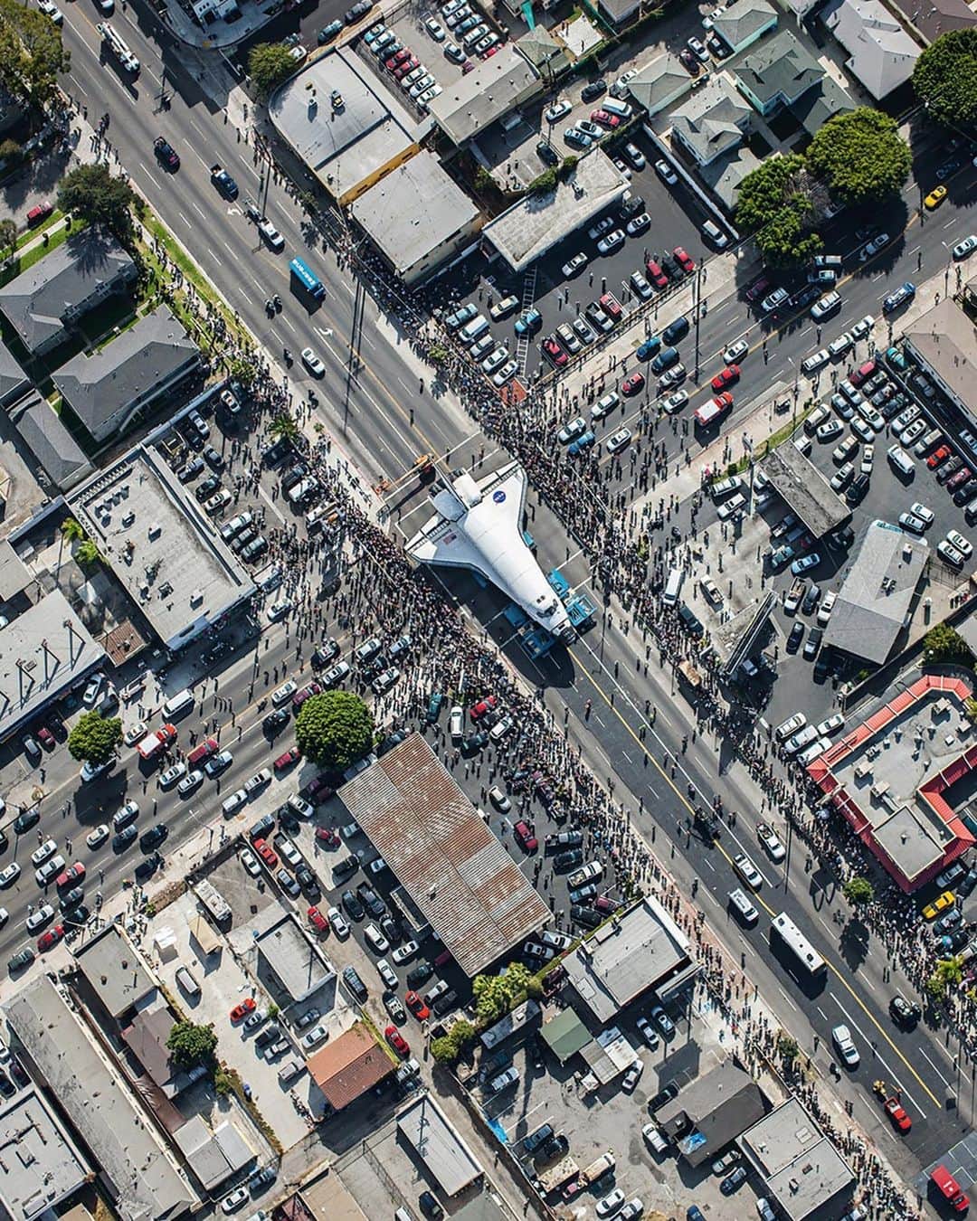 ナショナルジオグラフィックのインスタグラム：「Photo by @spencerlowell_ | When I learned of the space shuttle Endeavour's journey in 2012 through Los Angeles from LAX to the California Science Center, I was instantly inspired to create this image. I researched the route of the shuttle, selected the ideal day, and chartered a helicopter. To achieve the most parallel view, I stood on the struts of the helicopter as it banked. As a photographer with a love of science, this image resonates deeply with me, juxtaposing humanity's terrestrial existence with our cosmic aspirations. #WorldSpaceWeek」