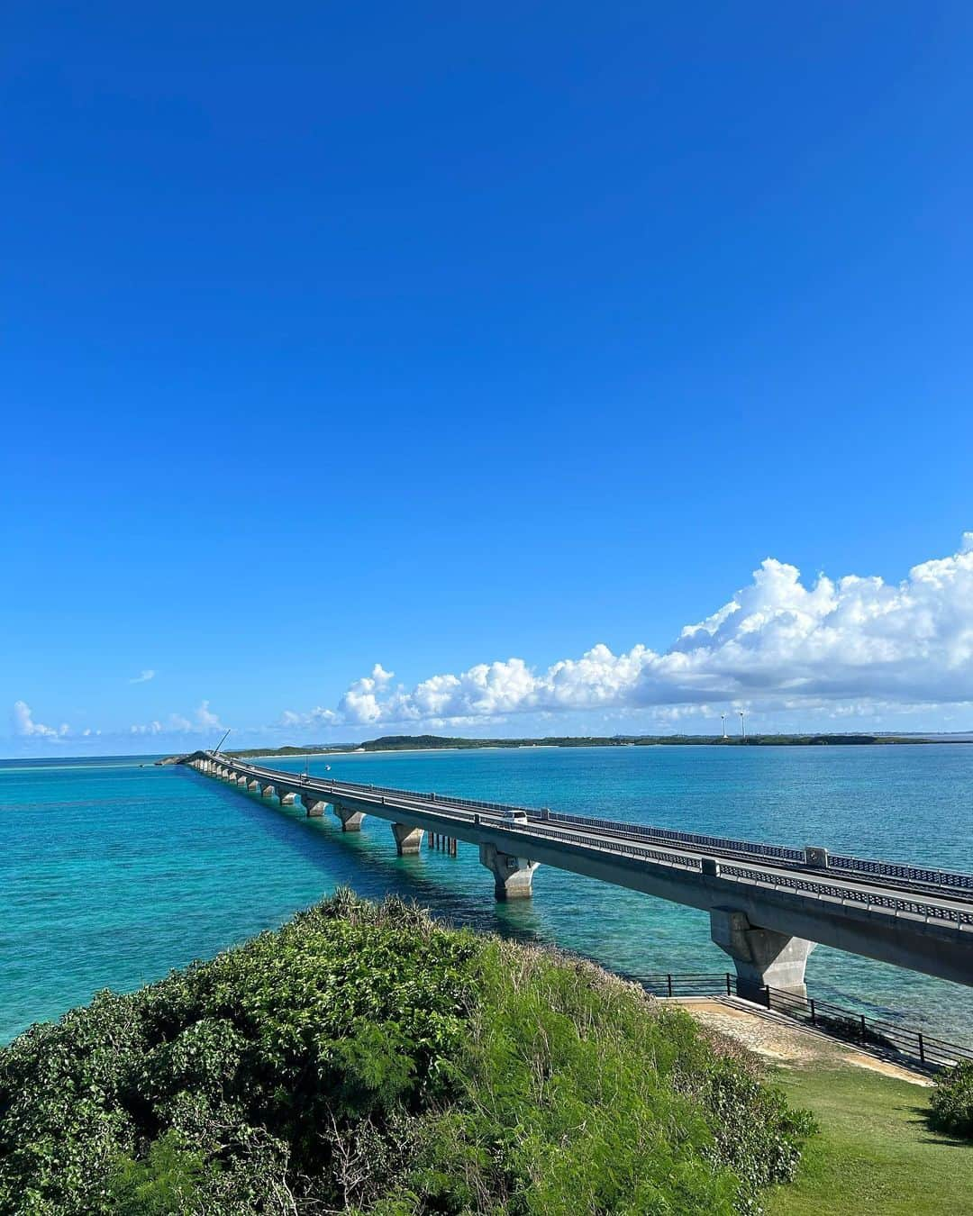 金泉紗恵子のインスタグラム：「. 【宮古島　池間大橋　海美来】 池間大橋を渡ってすぐ右側にあるお土産があるエリア✨ 一番奥の海美来（かいみーる）の展望台からの景色😍 何かを買ったり食べなくても、お店の中から展望台へ行けます👍  この日は空を見たら池間が晴れてそう！と思って向かってみて大正解🙆‍♀️ 宮古島は山がないので、空を見てどの方向が天気が良さそうか悪そうか分かりやすいのも良いところ😊  海美来ではサザエそばと紅芋もちをいただきました🥹 いやーサザエそばのスープもとっても美味しくて最高でした🤍 紅芋もちも何度も食べてるけど美味しい😆 濃厚でぎっしりなので、お腹いっぱいになります！ マンゴージュースも美味しい！と言ってる方が多かったです😌 1人でも入りやすく、お店の方もとても優しいです👍  ハイシーズンは駐車場が混むので待つのは必須💦 でも晴れていたら最高の景色を楽しめるので、オススメスポットです🥰 . #宮古島 #池間大橋 #池間島 #海美来 #展望台 #池間ブルー #サザエそば #紅芋もち #沖縄 #1人旅 #女子旅 #沖縄旅行 #宮古島旅行 #宮古島グルメ #宮古島観光 #宮古島観光スポット #宮古そば」