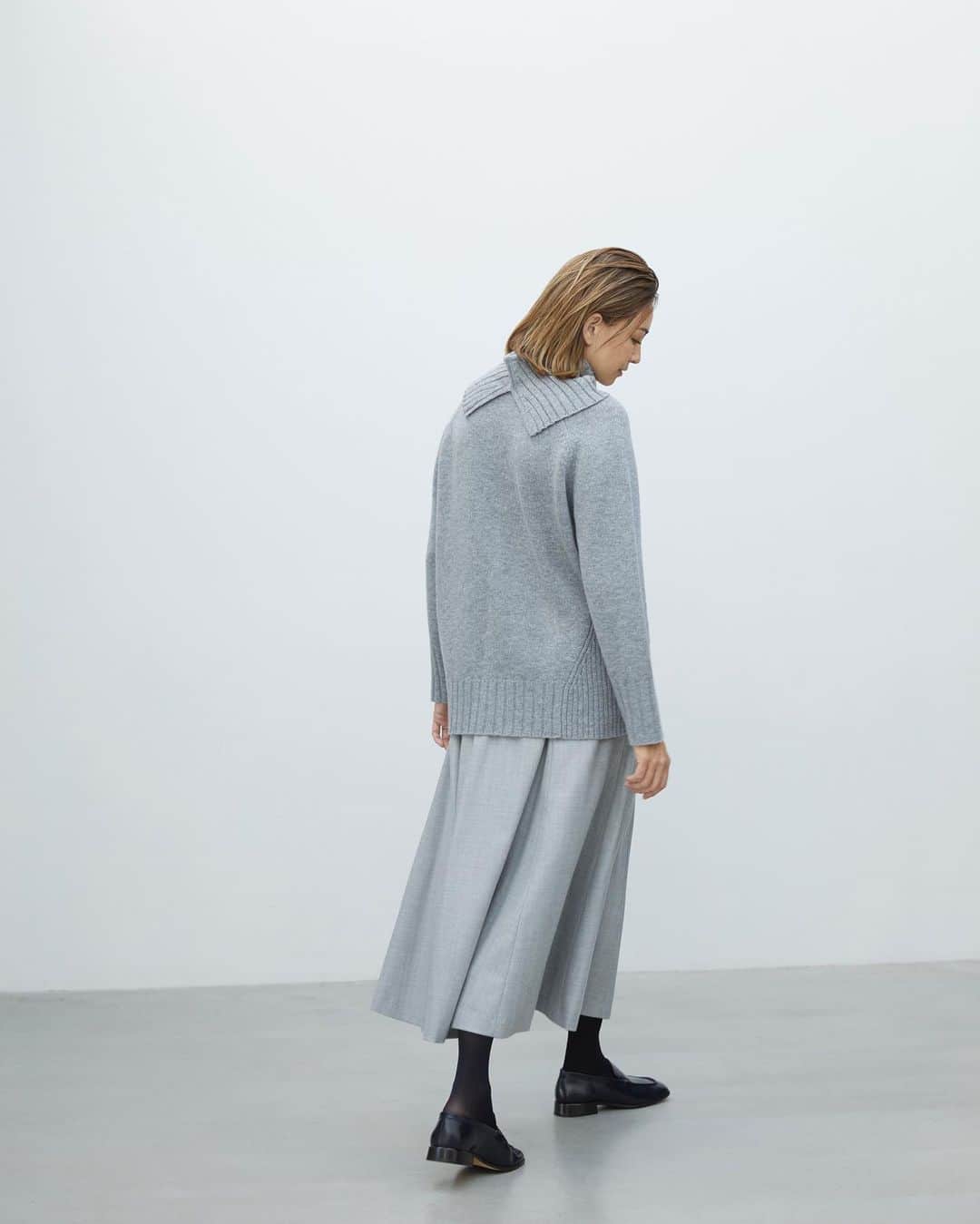 Theory luxe official account.のインスタグラム：「［FALL 2023 COLLECTION -October-］  厳選されたウールカシミヤで編み上げたプレーンなクルーネックニットは、右脇に配したリブ編みパターンがさりげないアクセントに。  「取り外し可能なスリット入りのタートルネック型リブ編みスヌードで、着こなしアレンジを楽しみたい一着。落ち感の美しいドレープスカートをライトグレーでつなげると、Ｉラインシルエットが強調されてすっきりとした印象に」（リタさん）  #theoryluxe #セオリーリュクス #デザインニット #ワントーンコーデ #フレアスカート」