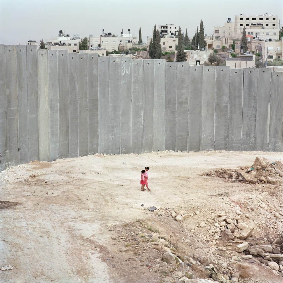 Magnum Photosのインスタグラム：「@alessandra_sanguinetti: "I first traveled to Palestine in 2003 and 2004, and visited refugee camps in Gaza and Bethlehem. The resulting images document the lives and experiences of young Palestinians growing up amidst the decades long Israeli military occupation, facing daily dangers and human rights violations."⁠ ⁠ Since Hamas launched an unprecedented attack on Israel via the Gaza Strip on Saturday, October 7, killing hundreds of civilians, Israel has dropped more than 1,000 tons of bombs and 2,000 unspecified weapons, so far killing around 600 people, including 78 children, and wounding thousands, according to the Gaza Health Ministry. The U.N. humanitarian agency reports that the strikes have displaced almost 125,000 Palestinians in Gaza.⁠ ⁠ Today, Israel has cut off food, water and fuel from the two million people trapped in Gaza.⁠ ⁠ PHOTOS (left to right): ⁠ ⁠ (1) Separation wall. Abu Dis. 2004. ⁠ ⁠ (2) Zanya and Jasmine overlooking the construction of the separation wall that will isolate them from their town. Abu Dis. 2003. ⁠ ⁠ (3) Riham Khaled Abuheen was shot in the eye by IDF forces during a raid on her building. Shajaiaya. Gaza Strip. 2003. ⁠ ⁠ (4) Landscape. Gaza Strip. 2003. ⁠ ⁠ (5) Hooda next to the door her mom died behind when Israeli soldiers blew through it. Aida refugee camp. 2004.⁠ ⁠ (6) Kids playing. Aida refugee camp. West Bank. 2004. ⁠ ⁠ (7) Schoolgirls. Bethlehem. West Bank. 2003. ⁠ ⁠ (8) Hadir Rizq in a destroyed house. Gaza Strip. 2003. ⁠ ⁠ (9) Schoolgirls looking back at Israel's separation wall and sniper tower. 2003. ⁠ ⁠ © @alessandra_sanguinetti / Magnum Photos」