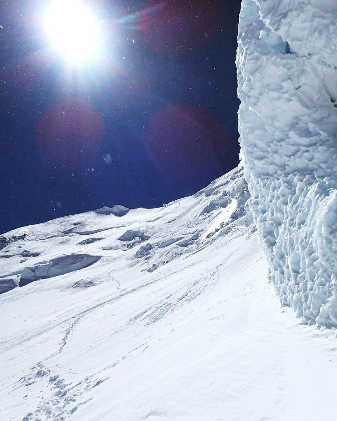 石川直樹さんのインスタグラム写真 - (石川直樹Instagram)「For Himalayas⑮#Shishapangma. シシャパンマに登頂できなかった。ぼくの目の前で、あまりにも壮絶な出来事が起こった。おそらく山岳史に刻まれる事件になる。見たことを正確に書く必要がある。これは自己表現ではなく、記録であるべきだ。 . 10月6日ABCを朝5時に出発した。インスタグラムには2200字という制限があるため、このあたりの過程はすべて割愛せざるをえない。 . 10月7日朝、周囲が少しずつ明るくなってきた頃、最後の急斜面の取り付きに、ぼくたちイマジンネパール隊とエリートエクスペディションの合同隊が到達した。 すると、後ろからテンジェンラマ率いるジーナたちがやってきた。ラマはクリスティンハリラと14座登頂を終えたばかりの猛者で、ジーナが雇った最強シェルパである。 . ラマに率いられたジーナたちは鬼気迫る速さで、ぼくたちを追い抜いていった。Fixロープは当然ないから、ラマはダブルアックスで先頭を行き、ロープを結んだジーナをガンガン引っ張っていった。その先には、エリートエクスペディション隊から抜け出たアンナたち3人がいた。 . ここから、「アメリカ人女性初14座登頂」というタイトルを賭けた、アンナ（＋シェルパ2人）VSジーナ（＋シェルパ2人）の仁義なき戦いが始まった（アンナもジーナも、共に13座に登頂、シシャパンマが最後の山だった。この競争の無意味さ、或いは、この競争から引き起こされたと言ってもいい今回の遭難に関する推察は、また別の機会に）。 そして、その次、3番目に、ぼくとキルーシェルパがいた。キルーはK2冬季初登頂を果たした10人のネパール人の1人で、ぼくのザイルパートナーとしては、十分すぎるほどの実力者だった。 . ぼくらを追い抜いたラマたちは左から右へまわりこむルートをとった。対して、アンナたちは直登して右へまわり込むルートをとった。 . これが運命の分かれ道だった。 . 彼女らを後ろから追う形になった自分は、自信ありげに左にルートをとったラマのほうが正しいだろうと踏み、アンナではなく、ラマ＋ジーナのほうのルートに進んだ。 強風が吹き荒ぶなか、左から右へまわり込むと緩斜面となり、ぼくとキルーは一息つくことができた。対決状態の2チームの姿はすでになく、先に進んでいた。ぼくとキルーは、先行2チームを追う形で、長いトラバースを開始。 . トラバースをすぐに終えて、右手に直登していったのがアンナたちで、ジーナたちは右手に折れることなくさらにトラバースを続け、そのずっと先から上へ、直登していくのが見えた。 つまり、先行2チームは違うルートで、それぞれの頂を目指していた。 ぼくたちの見立てでは、割と直近にシシャパンマに登頂した経験をもつラマが導くルートが正しく、アンナたちは、稼いでいる標高では優っていても、頂上を間違えていて勝負はついていたように思えた。 . ぼくとキルーはトラバースを続け、写真にも写っている、右にデカいセラック（氷塊）のある地点で、行動食を食べることにした。トラバースはまだまだ終わらないが、その先に休めるところがないように思えたからだ。 . すると、その先で、上からチリ雪崩がくるのが見えた。ぼくとキルーはセラックに守られて無傷。が、途端に無線が交錯していった。誰かが流されたらしい？それがアンナたち3人だとわかり、ただ事じゃない様子が、数分後には伝わってきた。 . しばらくすると、流された3人のうち、カルマというシェルパがなんと生きていて、アンナともう1人が見つかっていない状態であることを把握した。ぼくの目視では生きているのが奇跡、と思われる標高差の滑落だった。 . 先に進んでいたラマやジーナが、アンナたちがぶちあたった雪崩を知っていたのかはわからない。無線の周波数はイマジンとエリートは同じだが、ラマたちは違う周波数の無線を使っていたからだ。 . これは、ジーナやラマの名誉のためにも言っておく必要があるが、彼女たちは、この1回目の雪崩でアンナたちが流されたことを知らなかった可能性がある。別ルートで、離れたポジション、しかも似通った標高にいたわけで、自分たちの登攀に夢中だとすれば、ジーナたちは、アンナたちが流されたかどうかなんて確認できなかったのではないか、と。 . 結果的にラマとジーナたちは、登り続けた。 3番手に位置していた自分とキルーは、はるか後方にいたミンマGと無線で連絡を取り合い、引き返すことを決めた。アンナたちが流された最初の雪崩で「これ以上進むのは危険」と判断したからだ。それが、この写真を撮った7800mくらいの場所である。 . が、話はここで終わらない。 . 引き返しはじめ、一息つける緩斜面まで戻りきる直前に後ろを振り返ると、また雪煙があがっている？2度目の雪崩が起こり、ジーナやラマが登頂直前に流されたのだ。 ぼくが撮ったこの写真に、小さくジーナたち3人が固まった状態で写っている（2枚目）。あと50mくらいで頂上だと思うが、どうだろう。 . 2度の雪崩に最も間近で遭遇し、アンナやジーナたちと一番近くにいたのが、自分とキルーだった。シシャパンマは彼女らの遭難によって今シーズンの閉鎖が決まった。海外のメディアが取り上げはじめている今、まず一報をここに記す。」10月10日 7時58分 - straightree8848