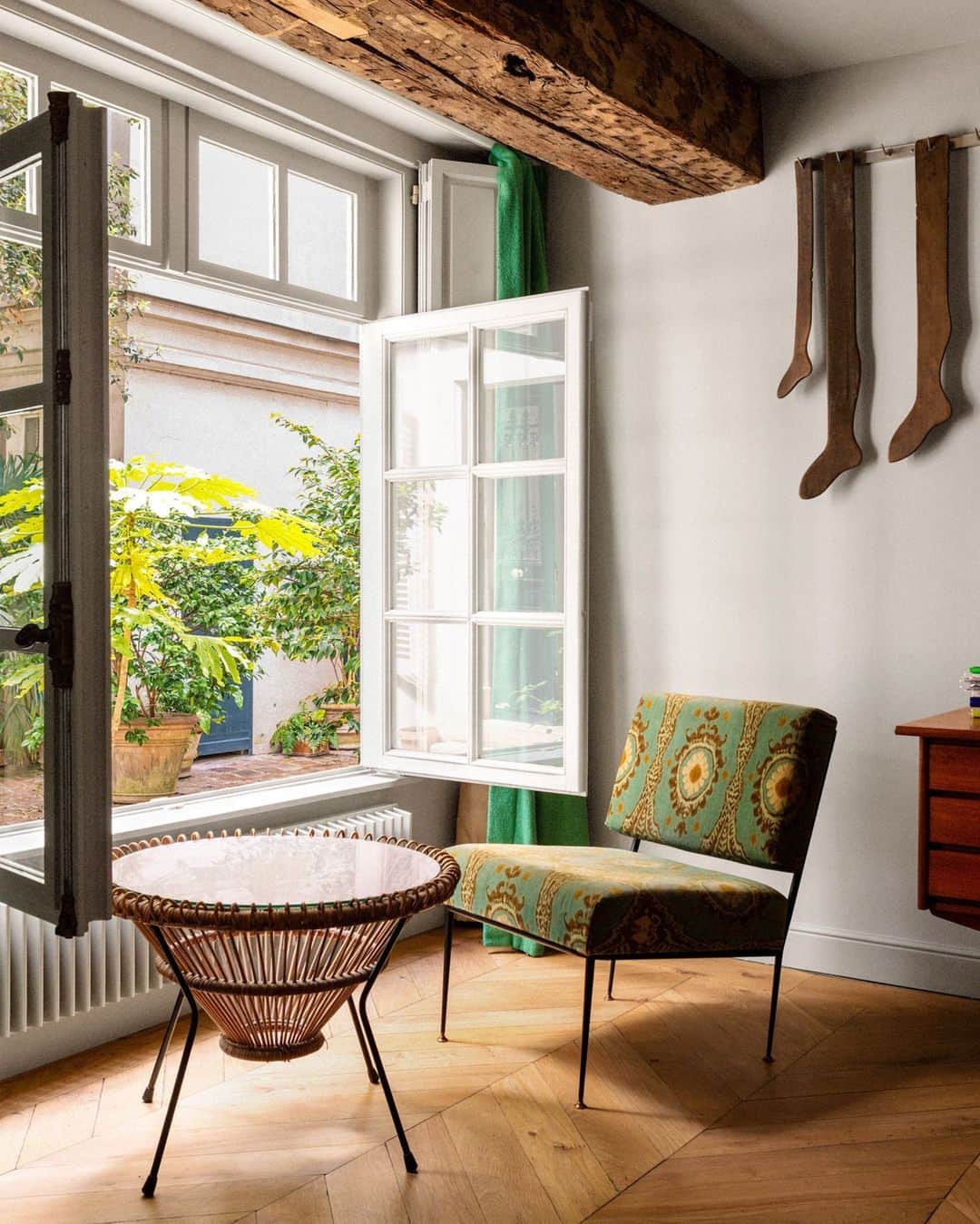 のインスタグラム：「In Paris, even old socks can be poetic. This light-filled bedroom located on the ground-floor level of a quirky 18th-century triplex designed by Retrouvius (@retrouvius) is a masterclass in effortless design. Antique stocking templates hang, nailed onto a metal rod, above a vintage Italian chair in a @lewisandwood fabric. For the palette, homeowner Leila Brink wanted colors that were “soft and calm,” she says, like earthy greens and buttery yellows. Leave it to designers Maria Speake and Adam Hills to turn an old apartment with potential into a beautiful home that’s not overly designed.   Click the link in bio for the full tour of this Paris Triplex, as featured in our October 2023 Change Issue. Written by @danathomasparis. Photographed by @theotennant1.」