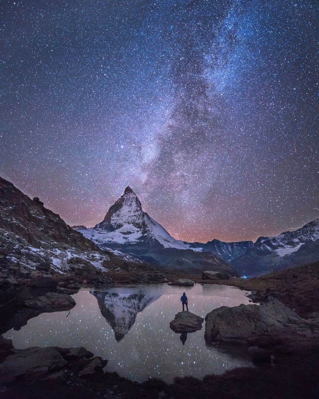 National Geographic Travelのインスタグラム：「Photo by @chrisburkard | I've found landscapes inspiring but also our interaction with them beautiful and worthy of documentation. On a cold night in 2015, Stellisee, a lake in Zermatt, Switzerland, seemed like the perfect place to capture the Milky Way juxtaposed with a single viewer. A notable lack of wind allowed for a reflection to emerge, providing the moment I was looking for—and one I hoped others would imagine themselves in when seeing the photo. #WorldSpaceWeek」