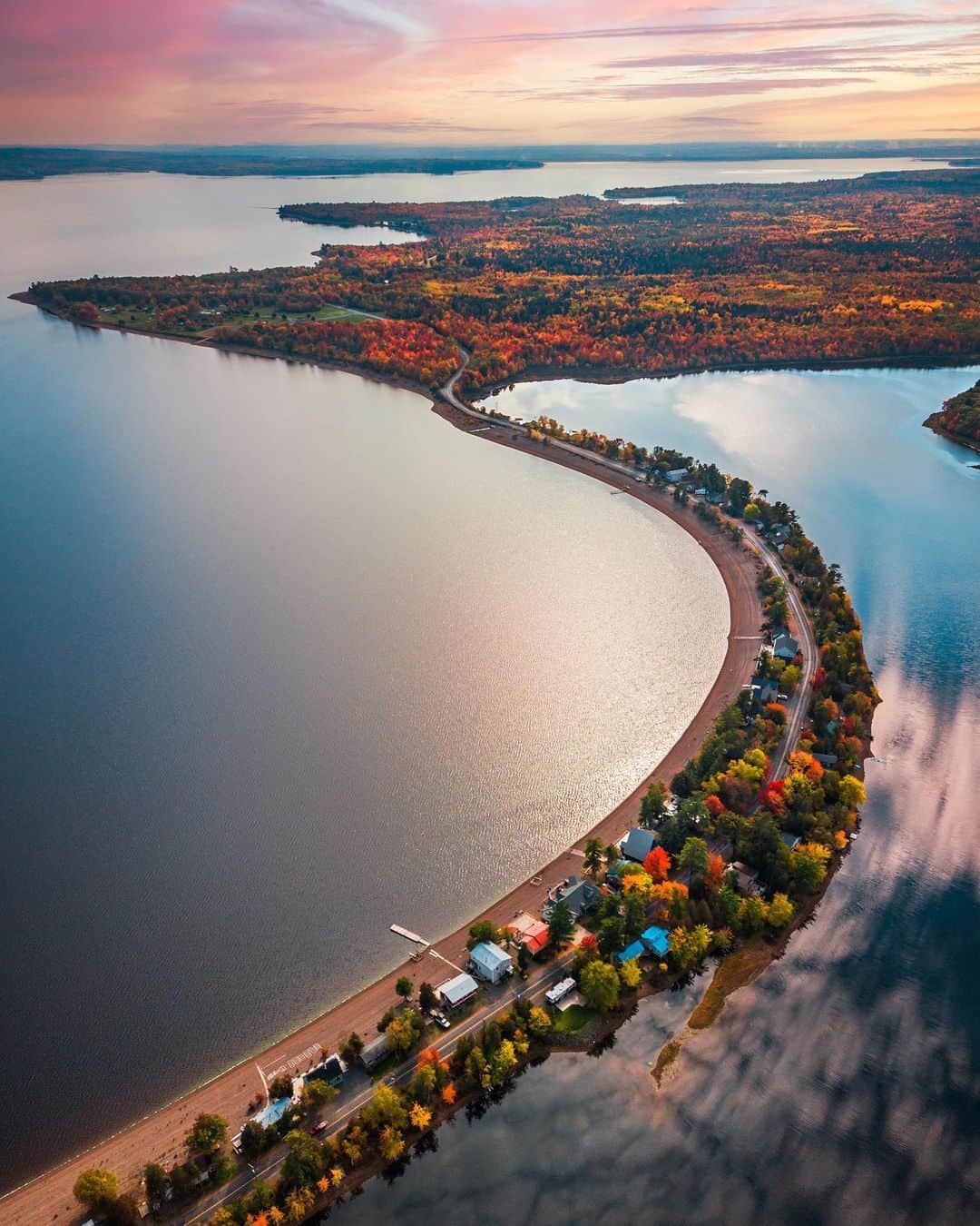 Explore Canadaのインスタグラム：「Fall views across a grand playground.   Grand Lake is the largest freshwater lake in New Brunswick, stretching over 32 kilometres (20 miles) long which makes it a water sports paradise! It’s also a bird watching haven and home to the most stunning sunsets.   📷: @st3mm3r  📍: Princess Park, Grand Lake, @destinationnb   #ExploreNB #ExploreCanada  Image description: An aerial view of the Princess Park isthmus; a tree-lined road flanked on both sides by water, and leading to a peninsula dotted with bright, Autumn coloured trees. The evening sky has shades of pink and orange.」