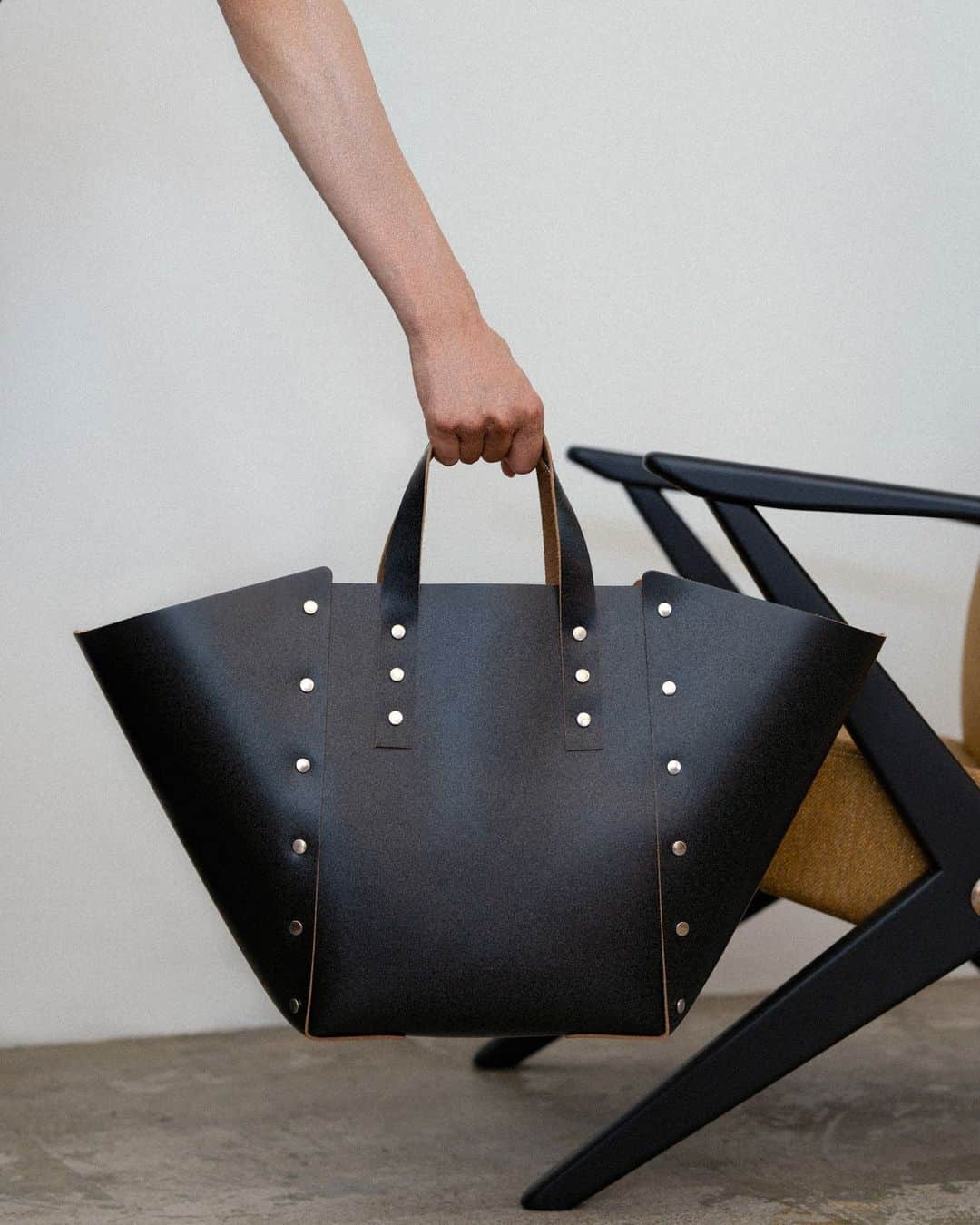 エンダースキーマのインスタグラム：「“assemble” assemble hand bag wide M  “assemble” is a collection of leather items that are 'assembled' and formed by riveting leather patterns, without sewing processes, like making a plastic model kit. The simple, unlined structure gives the products a more minimal look and highlights the natural color of the interior cowhide against the gloss leather exterior.  #assemble #henderscheme #2023sa」