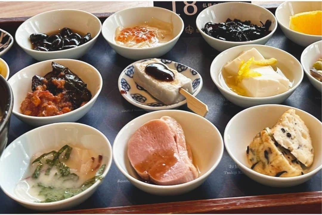 レッツエンジョイ東京さんのインスタグラム写真 - (レッツエンジョイ東京Instagram)「お寺のカフェの「朝ごはん」🍚✨  「築地本願寺カフェTsumugi」は、お寺の境内にある人気カフェです。とくに評判なのが「18品の朝ごはん」という朝限定メニュー。小鉢に盛り付けられた16種類のおかずと、お粥、おみそ汁がセットになっています。  阿弥陀さまがたてられた48誓願の中心となる「あなたを決して見捨てない」と願い誓われた「第18願」。この18番目の誓願にちなんで18品をそろえたという、なんとも豪華な朝ごはんです。  築地本願寺を眺めながら、忙しい日常を忘れてほっと一息、癒やしの朝活をしてみては？  🔸築地本願寺カフェTsumugi @tsukiji_hongwanjicafe 📍東京都中央区築地3-15-1　築地本願寺インフォメーションセンター内 🚉築地  #レッツエンジョイ東京 #おでかけ #おでかけスポット #東京 #築地 #築地本願寺 #築地本願寺カフェ #築地本願寺カフェtsumugi #tsumugi #和カフェtsumugi #18品の朝ごはん #朝ごはん #和ごはん #和食 #朝食 #朝活カフェ #モーニングカフェ #モーニング #和カフェ #東京グルメ #東京観光 #築地グルメ #朝ごはん部 #朝活 #あさごはん #朝ご飯」10月11日 19時01分 - lets_enjoytokyo