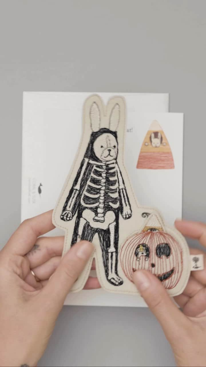 コーラル アンド タスクのインスタグラム：「Send a Halloween Hello with our Bunny Skeleton Felt Friend! 🐰 Bunny is dressed as a skeleton for Halloween. Peeking out of the Jack-o-lantern is baby bunny in a candy corn costume. Baby bunny can be removed from the felt pocket and worn as a finger puppet. Our Halloween Bunny Felt Friend comes with a notecard and an envelope. #coralandtusk #halloweencard #trickortreat」