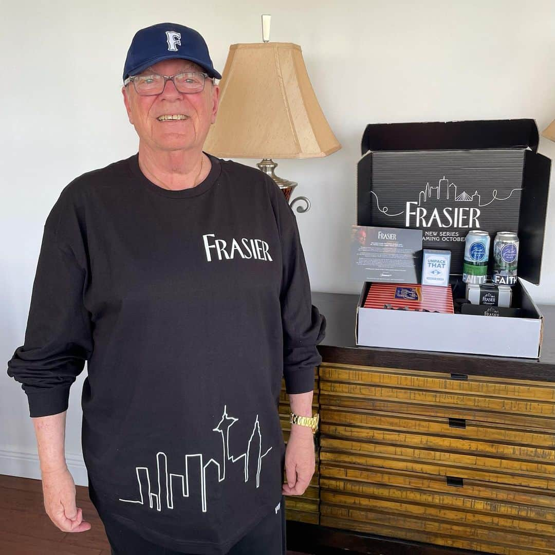 ミッチェル・コリンズのインスタグラム：「Ok the #Frasier people are spoiling us now… just got a whole FRAZHE GIFT SET celebrating tomorrow’s premiere ft. a frasier scented candle, box of cakes, and @frasier shirt + F hat, seen above modeled by my dad. Even the cat got something! (Empty box which plays Frasier theme…) The show premieres tomorrow Oct 12 on @paramountplus! My mom called me and within 3 minutes got “cake all over the phone.” #paramountpluspartner」