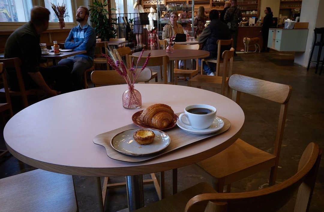 平岡佐智男さんのインスタグラム写真 - (平岡佐智男Instagram)「北欧新婚旅行12（北欧カフェ巡り2）：ヘルシンキの信じられないほど美味いクロワッサン  ヘルシンキについて3日目の朝だ。 朝はアパートを一人抜け出して、カフェを巡ることにしていた。 毎朝、KAFFA ROASTERYに行こうと思っていたが、なんと土曜日曜は営業時間が違うと言うことに気づいた。 平日は8時からやってるが、土曜は10時かららしい。日曜は休みだ。  と言うことで、近隣のカフェを探すことにしたのだが、土曜の朝からやっているカフェがなかなか見つからなかった。  そんな中、見つけたのがLEVAIN。ベーカリーカフェで店内にパン工房もついていた。 平日8時から、土曜は8時半、日曜は9時と言う刻み具合だ。  　  早朝オープン直後にも関わらず、とても賑わっていた 店内に入ると広々としていて、ショーケースや壁にたくさんのパンが綺麗に並べられていた。 2階建てになっていて、いろんな座席タイプがあっていい。  　  いろんな種類のパンがあったが、フィルターコーヒーとクロワッサン、そして朝から欲が出てしまいエッグタルトも注文した  　  ちなみに、この旅ではデジタルカメラ（RICOH GR3）とフィルムカメラ（CONTAX ARIA）を常に持ち歩いていて、気分によって撮り分けていた。 6枚目がデジタルで7枚目がフィルムだ。ピントを外しまくっているし条件が色々違うので比較にならないが、なんとなく味わいの違いがあっていい。 その辺りも楽しんでいただけたら嬉しい。  フィンランドやスウェーデンではコーヒーは備え付けのポットから自分でセルフ注ぎパターンのお店がほとんどだ。 カップも積まれていてそこからどうぞのパターンも多い。 コーヒーが生活に根付いてる感じがしてそれはそれでいいなと思ってしまう。 LEVAINではオーツミルクも置かれていて、この旅でオーツミルク好きになった身分としては、楽しくなってしまった。  さて、コーヒーと一緒にいただいたクロワッサンだが、信じられないぐらい美味しかった。 もう一度言わせてほしい。本当に信じられない美味さだ。 クロワッサンの繊細かつ存在感のある生地の層が何枚も重なっていて自分の歯がクロワッサンの層をパリパリパリと破っていくのが気持ちいい。その先にしっとりしたゾーンにたどりつくと、甘いバターの香りと小麦の香り、なめらかな質感がしっとりと口の中に広がる。  おそらくフィンランド1美味い。  これフィンランド補正がきいてて美味しいと感じているのか、？と思うが、毎回そんなこと思っているなと思い、本当に美味しいんだなと納得した。  LEVAINはヘルシンキに3店舗ほどあるらしい。  この地区にアパートを借りて本当に良かったと心から思った。  妻にも食べさせないといけないと言う使命感にかられたが、勝手に買って帰ると勇足になってしまう可能性があるので、話して興味あるそうだったら後日買うと言うテクニックも身につけていた。ここはNOサプライズでいいという冷静な判断も必要だ。  家に帰ると、妻は妻で市場で買ったベリーでソースを作り、ヨーグルトと合わせてフィンランドを楽しんでいた。  めっちゃ美味そうやんと伝え、後日ヨーグルトとクロワッサンを交換することにした。  #カフェ #フィンランド #北欧 #クロワッサン #旅行 #海外 #新婚旅行 #旅行記 #クロワッサン #カフェ巡り #海外旅行 #levain」10月12日 9時00分 - sachio_coffeeforme