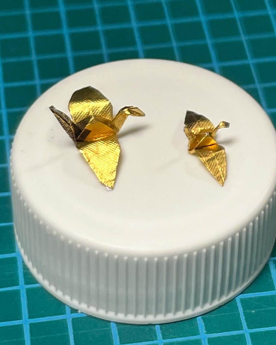 高野寛のインスタグラム：「左:2cm×2cmの紙 右:1.5cm×1.5cmの紙 台はペットボトルのフタ  パラフィン紙なら、もう少しキレイに小さく折れるかも…」