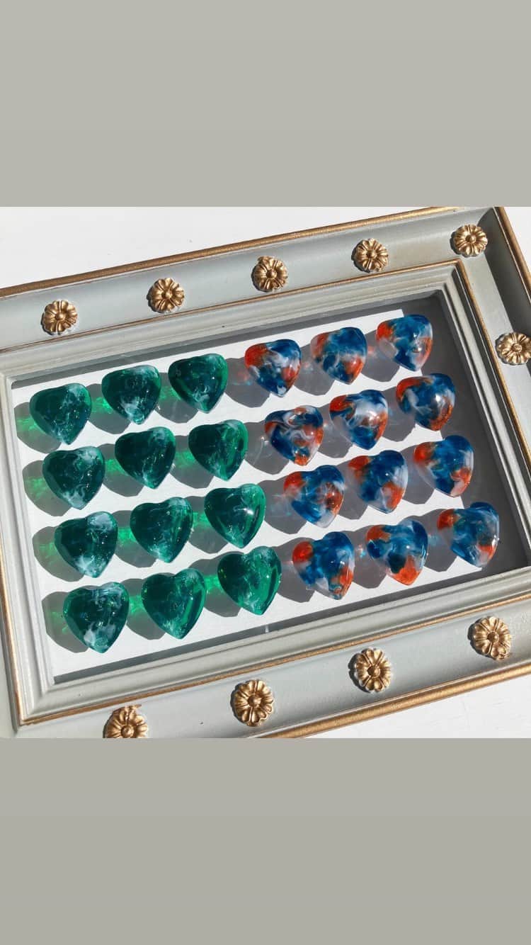 Fukiko-マルベリコのインスタグラム：「一つ一つ模様を描いて制作した マーブル模様のハート💚💙🧡  ずらっと並べてみました！ うるツヤで宝石みたいです✨  こちらを使用した指輪は、 14日(土)21時より販売いたします！😊  よろしくお願いいたします！  #ハンドメイドアクセサリー　#レジンアクセサリー #グリーン #ブルー #オレンジカラー #マーブルカラー #ラメ #キラキラ #💍 #ハンドメイド #指輪 #kawaii #handmadejewelry #ring #handmade #귀여워 #반지 #악세사리 #반짝반짝」