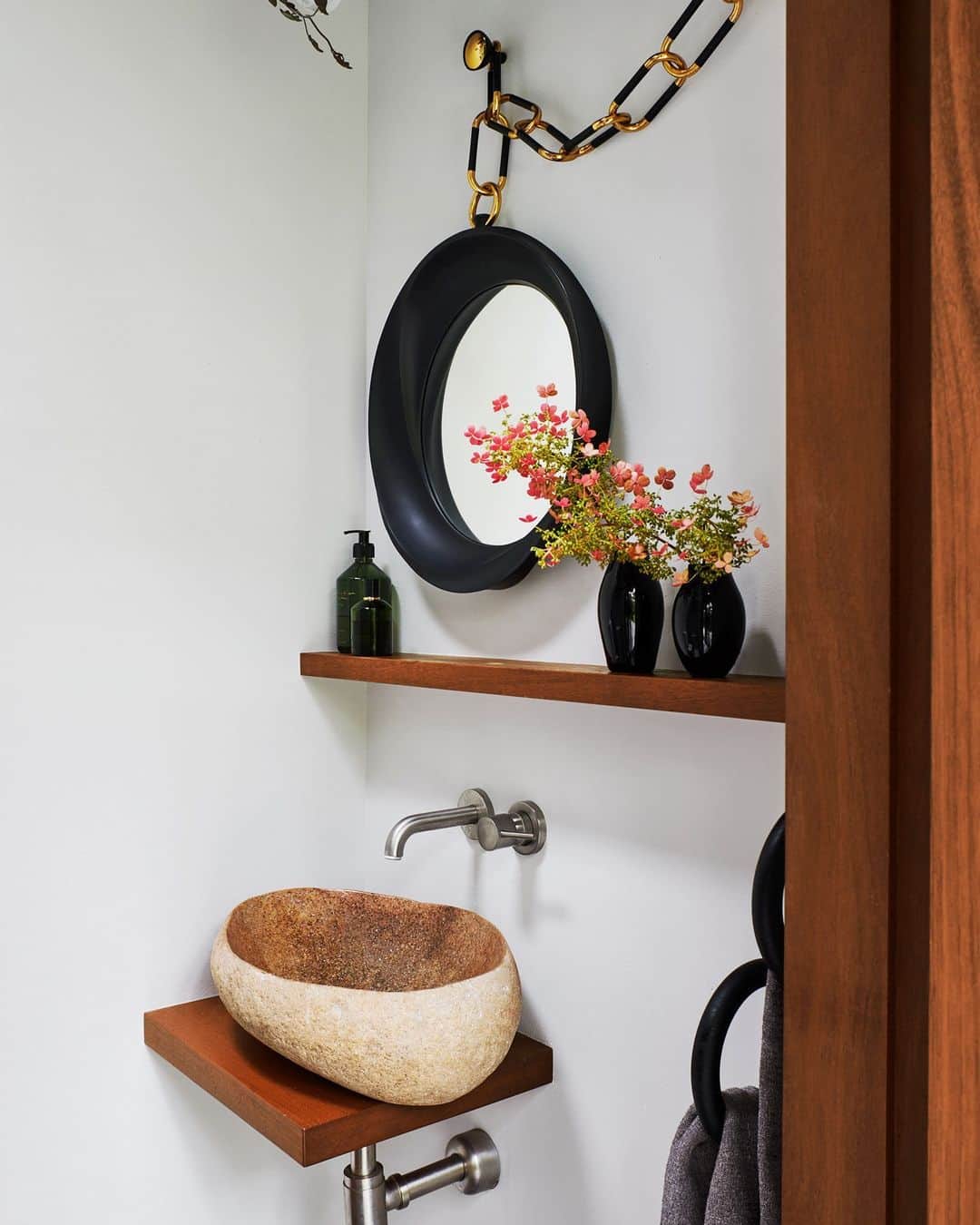 のインスタグラム：「Because bigger isn’t always better. This powder room speaks to the power of the elements, thanks to the careful curation of Carol Egan (@studiocarolegan) in her glass house located in the wooded hamlet of Amagansett, New York. The carved stone sink sits on a mahogany shelf. The fittings are by @vola.denmark and the vases by @tse_tse.associees. Give us some on-the-pot reading material, we might be in here  awhile.   Click the link in bio for the full tour of this ethereal glass house, as shown in our October 2023 issue. Written by @whatpaolasees. Photographed by @richardpowersphoto.」