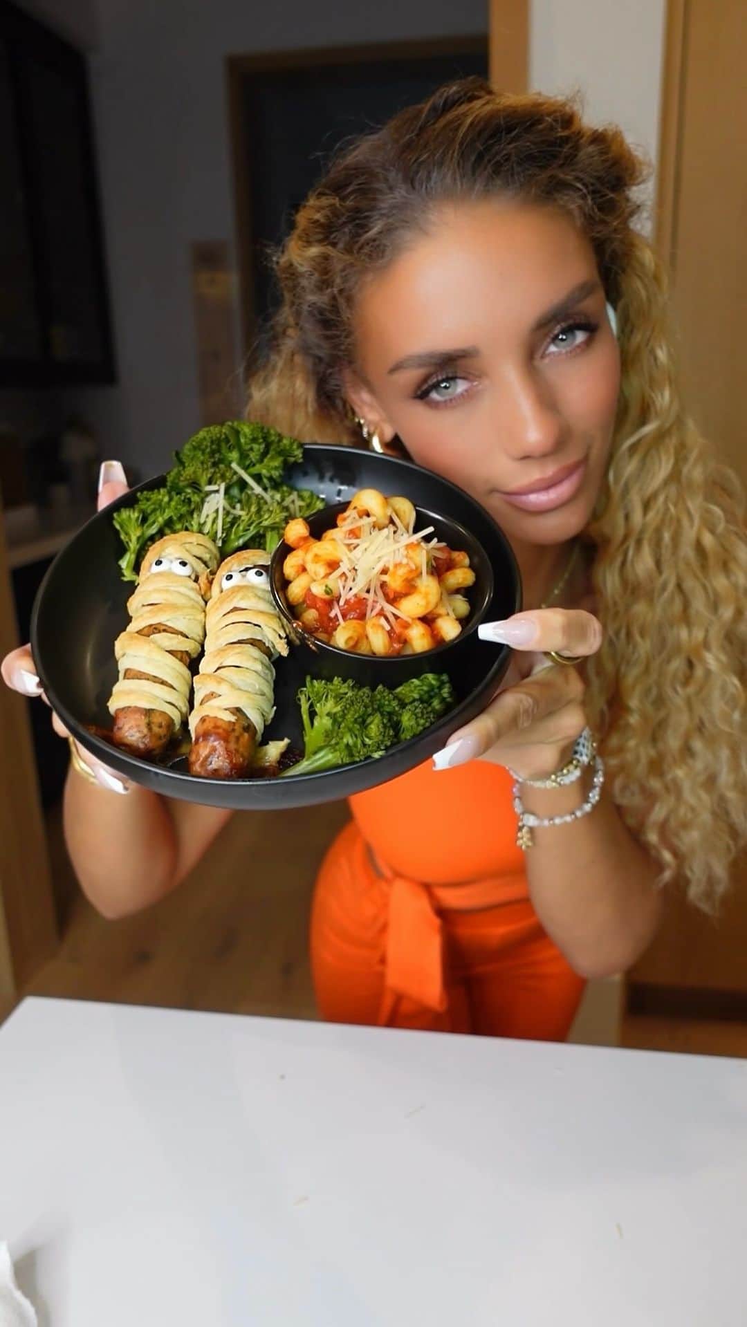 Jena Frumesのインスタグラム：「This was a super fun to make🧡 I served to my little man whole & then cut it up so relax in advance💀 I love making Halloween themed meals super excited for our next one! 🎃💀👻  How I made it;  •Sauté onions w/ olive oil & salt •Add Fully cooked Chicken sausage🍗   (or whatever protein you prefer)  •Cook for about 10 minutes on medium heat (This adds extra flavor and preheats them for next steps) •Roll out pastry dough with some flour 🥐  •Slice this strips to wrap around sausage to create your “mummy”  •Add butter for extra flavor🧈  •I heated in air fryer for 15 total minutes  •I used some ranch dressing to make the candy eyes stick 👀  Broccolini 🥦 •I boiled covered for about 15 minutes added a sprinkle of salt fl water before and after drained •Noodles🍝  •Boil your pasta 🍝 🤣」