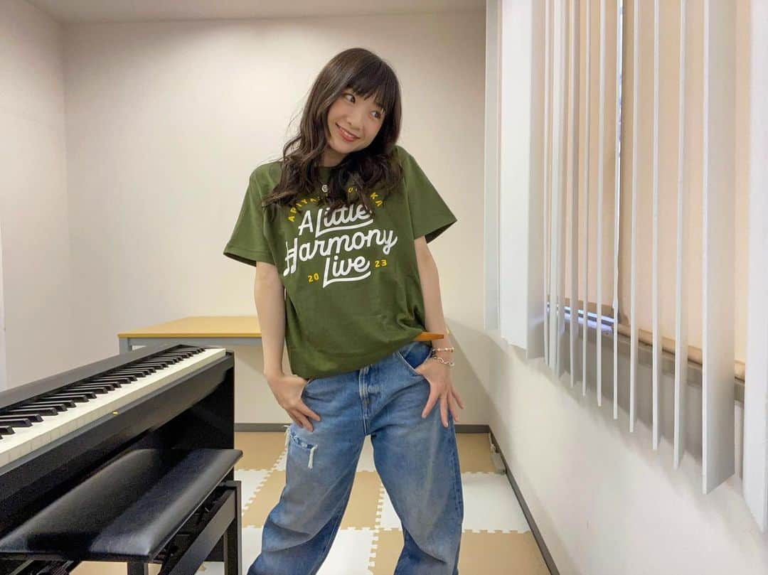 有安杏果のインスタグラム：「♪ ⁡ いよいよもうすぐスタートする弾き語りツアー 『A Little Harmony Live』のグッズを紹介します🙌 Tシャツは私のお気に入りカラーの2色でカーキとバーガンディ♪ ⁡ あとライブでは欠かせないタオル🎃 色めちゃくちゃ可愛いです🧡🤎 ⁡ 続いて、これからの季節には欠かせないフーディー(フード付きのパーカー)☃️ 使いやすい万能カラーにしました♪ ⁡ そして皆さんからリクエストが多かったラババン！ 色は今までにない季節イベント感満載に仕上げてみました🎄🍂 ⁡ あと今年の夏ツアーの時に嬉しくも大好評だったタンブラーの色違いを作りました☕️ 落ち着いた優しい色味のカーキです☘️ ⁡ そしてそしてこれは個人的にあったら良いなぁーと思って作ったスマホショルダー👜📱 ちょっとしたお出かけの時やリュックの時などにあったら便利だと思います😉 ⁡ ラストはついに私も時代に乗って作ってみたアクリルスタンド❣️ 少し照れながらも4種類の衣装を着て撮りました🙈 ⁡ ということで全12公演3ヶ月たっぷり楽しめるようにグッズも私のお気に入りを詰め込みました🥰 もちろんそれに負けないくらいライブもぎゅーぎゅーに詰め込んでます🐄🤍 皆さんに会えるのをめちゃくちゃ楽しみにしてます🎶 よろしくお願いします！ ⁡ #acoustictour #piano #guitar #弾き語り #alittleharmony #リルハー #グッズ #パンプキンイエロー #ピスタチオ #クリスマス」