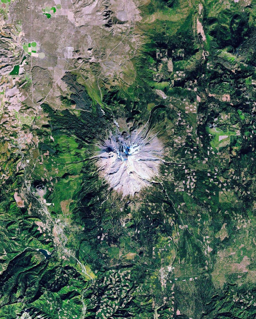 Daily Overviewのインスタグラム：「Mount Shasta is a potentially active volcano at the southern end of the Cascade Range in Siskiyou County, California. Rising 14,179 feet (4,322 m), it is the second-highest peak in the Cascades and the fifth-highest in the state. Surrounding the mountain is evidence of deforestation through clearcutting — a methodical practice of uniformly cutting down trees in a contained area. The process is controversial for its effect on the land’s topsoil, which is also removed with the trees, leaving patches of gray deforested areas.  Created by @dailyoverview Source imagery: @planetlabs」