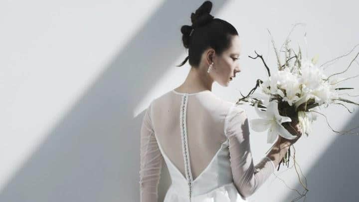 のインスタグラム：「nae.ATELIER 2023 new dress 【”molly”(モリー)】  上品な透け感のあるチュールのトップス。 素肌の上に線を描くように施した、 スタイリッシュなネックラインの縁取り。 背中のしなやかな曲線美を表現する、 背中心に並ぶくるみボタン。  露出の少ないデザインがモードさとスタイリッシュさを、 艶やかでハリが美しいミカドシルクのスカートが 王道のドレスらしさを醸し出すAラインドレスです。  バックスタイルにずらりと並ぶくるみボタンと 耳元のパールのイヤリングをリンクさせたコーディネートがお気に入りの一着です。  “molly” is A-line dress that has both royal and modern atmosphere. Skirt made of Mikado spreads out a lot and it makes the bride look dignified. Fabric covered buttons lined up in rows on the back and neckline bordered with white line on the sheer tops, made of extra thin tulle, are also design points to make modern atmosphere.  earrings @__ripsalis__   nae.ATELIER 東京都渋谷区恵比寿南1-13-2 EBISU COURT 101 TEL:03-6409-6369  #大好きと大切をすべてまとって #naeatelier #アトリエナエ #nae花嫁 #bridestyle #overseaswedding  #destinationwedding #elopementwedding #naebride #ウェディングドレス #シンプルドレス #Aラインドレス #molly」