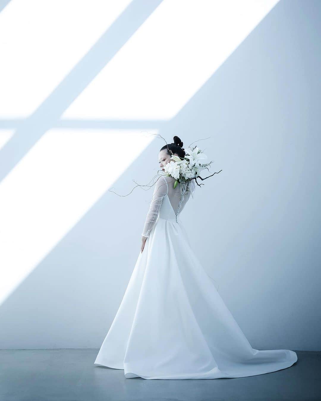 nae.ATELIERのインスタグラム：「nae.ATELIER 2023 new dress 【”molly”(モリー)】  上品な透け感のあるチュールのトップス。 素肌の上に線を描くように施した、 スタイリッシュなネックラインの縁取り。 背中のしなやかな曲線美を表現する、 背中心に並ぶくるみボタン。  露出の少ないデザインがモードさとスタイリッシュさを、 艶やかでハリが美しいミカドシルクのスカートが 王道のドレスらしさを醸し出すAラインドレスです。  “molly” is A-line dress that has both royal and modern atmosphere. Skirt made of Mikado spreads out a lot and it makes the bride look dignified. Fabric covered buttons lined up in rows on the back and neckline bordered with white line on the sheer tops, made of extra thin tulle, are also design points to make modern atmosphere.  nae.ATELIER 東京都渋谷区恵比寿南1-13-2 EBISU COURT 101 TEL:03-6409-6369  #大好きと大切をすべてまとって #naeatelier #アトリエナエ #nae花嫁 #bridestyle #overseaswedding  #destinationwedding #elopementwedding #naebride #ウェディングドレス #シンプルドレス #Aラインドレス #molly」