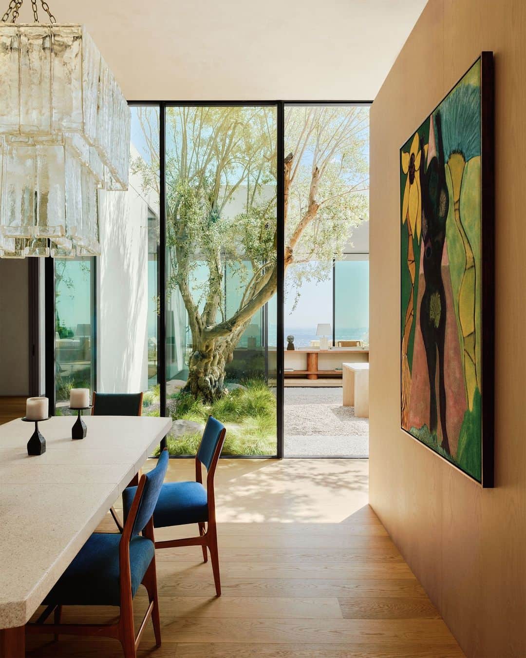 ELLE DECORのインスタグラム：「“You don’t want the architecture and interior design competing with each other,” says the owner of this ethereal Hollywood Hills house. Which is why he brought on architects Brett Woods and Joseph Dangaran (@woods_dangaran) and ELLE DECOR A-List interior designer Andre Mellone (@studiomellone) for the job. The architects used clever compositional elements—built-in wood niches, floor-through sight lines—to visually divide the home’s grander proportions into something more intimate. Overlooking the dining room is ‘Nude and Palms (Pink Triangle)’ by Chris Ofili. The vintage chandelier is by Venini, the vintage table by Paul T. Frankl, and the 1950s chairs are by Gio Ponti.  Click the link in the bio to tour the rest of this Hollywood Hills house, as featured in our November 2023 issue. Written by @isuredontknow. Styled by @amykchin. Photographed by @william.jess.laird.」