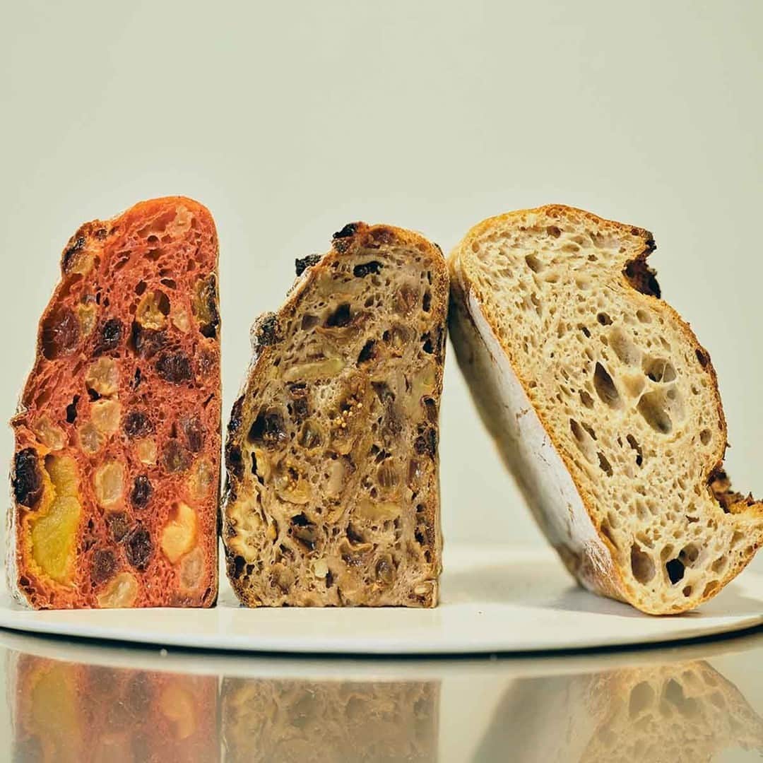 Hanako公式のインスタグラム：「常識が覆る！〈しかたらむかな〉の超高加水なパン   パンの種類や使う具材に応じて、粉とその配合、酵母を何種類も使い分け、最適なバランスを編み出す、この技巧的なプロセスが〈しかたらむかな〉らしい繊細で潤いに満ちた味わいを生み出しています。   写真左から、「いちご」「たわわ」「ヨカン」。 「いちご」と「たわわ」は同じ生地を使用。 「たわわ」はネーミングの通りイチジクもレーズンもオレンジピールも大ぶりで食べ応え十分。 「ヨカン」はライ麦を30%配合。ほよほよと柔らかくもっちり。限りなく液体なのでは？と思ってしまう初体験の食感。   一口ごとに、水分を抱え込んだドライフルーツが“ぷしゃー”と弾け、瑞々しいジュースがそこここでほとばしります。   📍しかたらむかな( @3ft.nakamura.official )  住所：東京都新宿区若宮町13-1 kif annex 101  【Hanako1225号_「美味しいパンには、理由がある 」】 #Hanako#Hanakomagazine #バゲット #パン好き#パン飲み#パンマニア#パンスタグラム #パン活 #パンアンバサダー #ハードパン #高加水パン」