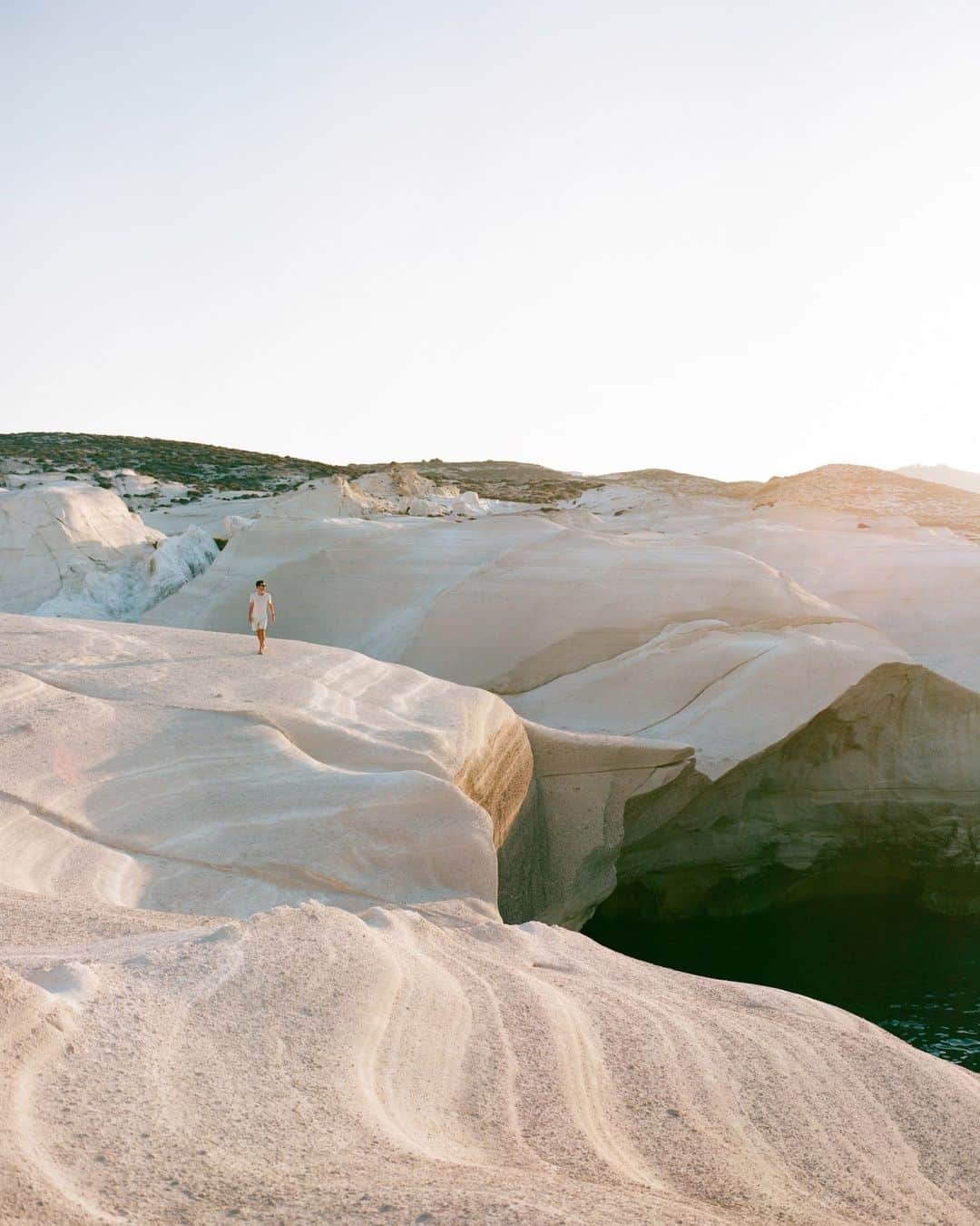 National Geographic Travelのインスタグラム：「Photo by @jessicasample | Carved by the relentless forces of wind and water over millions of years, the cliffs of Sarakiniko on the Greek island of Milos stand as a testament to the incredible power of nature. This lunar landscape, with its striking white rock formations against the deep-blue backdrop of the Aegean Sea, has captivated travelers and locals alike for centuries.」