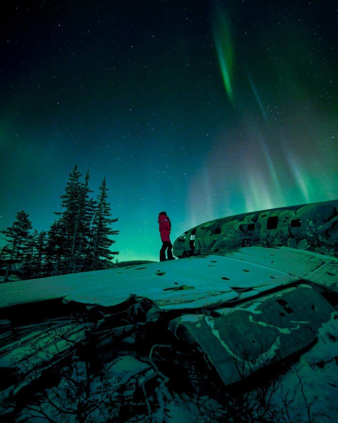 Explore Canadaのインスタグラム：「Are you planning to see the Northern Lights soon? Let us en-light-en you on how to catch the best version of nature’s very own light show.  Generally, the Northern lights can be seen up to 300 nights a year in Churchill, Manitoba—that’s around 10 months! However, since the night skies are relatively brighter in the summer season, it is recommended to visit sometime between September-March for a clear, visible view of the beautiful lights.   📸: @jdubcaptures 📍: Churchill, Manitoba @travelmanitoba  #ExploreCanada #ExploreMB  Image description: A person stands atop of an abandoned airplane’s left wing, gazing up at the hues of violet, indigo, and emerald green lights painted across the dark evening skies.」