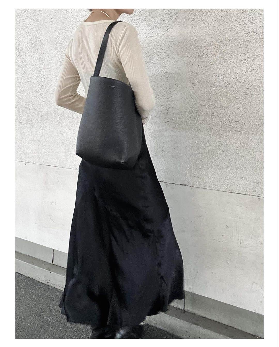 小山田早織のインスタグラム：「今日はサテンスカート🖤 透け感のあるリブカットソーと合わせてカジュアルに楽しみました♪ インナーは @danskin_japan のヨガウェアを着回しです🧘  #カットソー ... @deuxiemeclasse  #サテンスカート ... @bananarepublic_jp  #バッグ ... @therow   ちらっと通りがかったマルシェで次男の生まれ年のワインを購入しました🥳🍷  ワインセラーがない我が家では店主のアドバイスにより、クラフト紙で瓶をぐるぐる巻きにして野菜室で１７年寝かせる作戦です🍇  ワインならなんでもそのまま寝かせれば良いと言うわけではないらしく、熟成に向いたワインを見極めなければならないとのこと📝 長男の生まれ年ワインには出会えませんでした🤔🍇  これもまた運と出会いですね🤔  マルシェのおじさま勉強になりました😌  #私服  #スタイリスト私物  #生まれ年ワイン  #二十歳のプレゼント 🎁」
