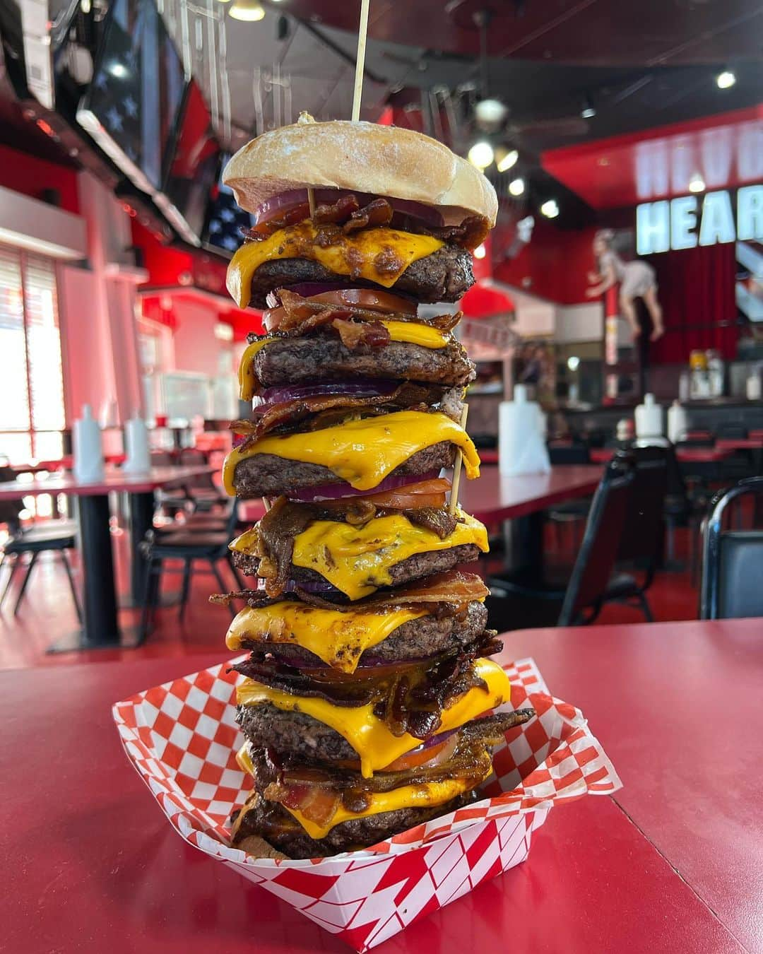 あこさんのインスタグラム写真 - (あこInstagram)「HEART ATTACK GRILL❤️‍🩹 お店に入ったら患者さんの服を着て食べるというコンセプト！周りの人達もみんな患者服で不思議な感じやった😂 私たちが食べたデカ盛りは 『OCTUPLE BYPASS BURGER 🍔』 高さ60cm、総重量約3kg、カロリーなんと20000kcal😂 パティは肉肉しくて食べ応え満点！カリカリのベーコンにチーズもたっぷり入って最高😍トマトと玉ねぎもたっぷりでバランスも良し🍅🧅 こういう大きいタワーバーガー食べるの夢やったからめちゃくちゃ楽しかったし美味しかった☺️💓 海外っていうこともあって周りのお客さんの反応が本当におもしろくて大食いってすごいんや…！ってなんか改めて感じた！笑 飲み物で頼んだ注射器のスムージーもストロベリーとマンゴーでさっぱりしてすごい美味しかった😍美味しくてドリンクだけで1.4L飲んでしまった🍓🥭 その後にデザートにかき氷も食べた！かき氷も超巨大サイズ😂 食べた後に写真撮ったらリップが落ちて血色悪くて本当に具合悪そうに見える😂 #せかくら #世界くらべてみたら #heartattackgrill #lasvegas #ラスベガス #デカ盛り #大食い #双子 #はらぺこツインズ #大食い女子 #먹방 #대식가 #먹팔  #먹스타그램 #大胃王 #モッパン #ความตะกละ #Ham ăn #Gula」10月17日 10時47分 - harapeko__ako