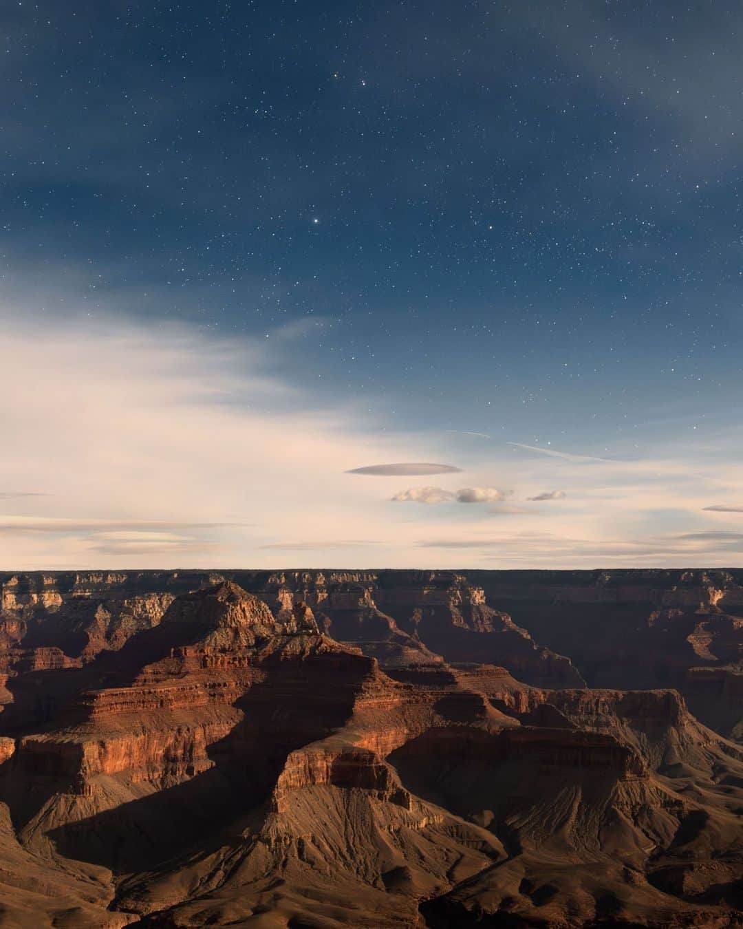 ナショナルジオグラフィックのインスタグラム：「Photos by @michaelgeorge | Taken at midnight in the Grand Canyon, this scene is deceptive: During a 10-second exposure, a nearly full moon illuminated the canyon, making it appear to be daylight when in fact it was almost pitch-black. The only giveaway that it’s not dusk or dawn is the wide array of stars in the sky. Swipe for a slight crop with more detail.   Admiring the canyon in the moonlight is a meditative (and quite cold) experience. The only moment that broke through the silence was when a woman who saw the lights on the back of my camera from quite a distance loudly announced to her family that she thought I was a UFO. For more stories behind the image, follow along @michaelgeorge.」