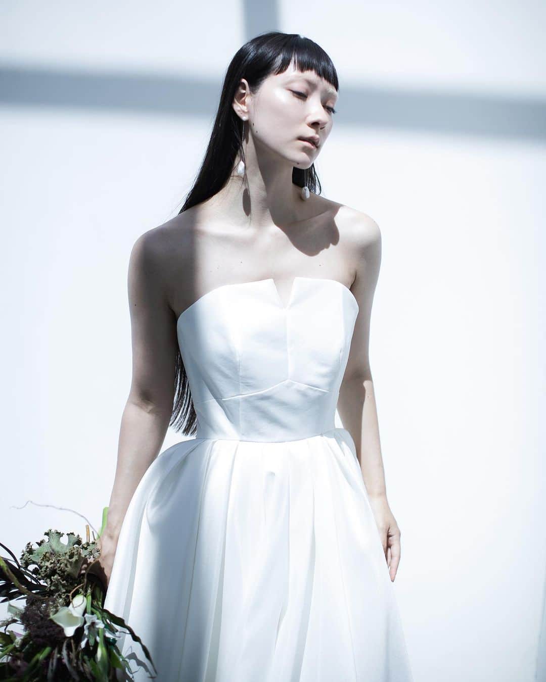 nae.ATELIERのインスタグラム：「nae.ATELIER 2023 new dress 【”edona”(エドナ)】  明るく、思い切りよく 人生を生きる女性をイメージしてお作りしたドレス。  胸元に多数入る直線的なカットが 視覚的に凹凸があるように見せ、 ウエストからふわりと広がるスカートが 全体のバランスにメリハリをつける 溌剌とした存在感を放つAラインドレスです。  “Edona” is A-line dress made of Mikado-silk, for the brides who live brightly and positively.  The many straight cuts on the chest parts and the skirt that gently spreads out from the waist make sharpness to the overall balance of the body.  nae.ATELIER 東京都渋谷区恵比寿南1-13-2 EBISU COURT 101 TEL:03-6409-6369  earrings @__ripsalis__   #大好きと大切をすべてまとって #naeatelier #アトリエナエ #nae花嫁 #bridestyle #overseaswedding  #destinationwedding #elopementwedding #naebride #ウェディングドレス #シンプルドレス #Aラインドレス」