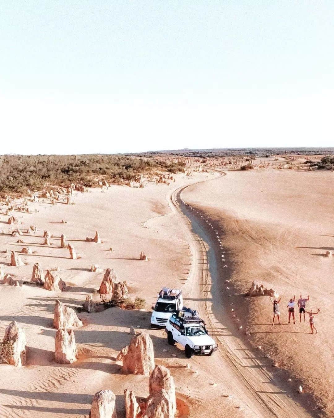 Australiaのインスタグラム：「You have arrived at your destination... and it's not Mars! 👽🧑‍🚀 Welcome to the #PinnaclesDesert in @westernaustralia's #NambungNationalPark - captured here perfectly by @saltyvanlife. Home to the Whadjug and Yued people, these otherwordly rock formations in @australiascoralcoast were formed nearly 30,000 years ago after the sea receded and left deposits of seashells. Pretty cool, right? 🤯 An easy 2-hour drive from Boorloo (@destinationperth), the #Pinnacles are spectacular at any time but are especially breathtaking at sunset, so we suggest staying longer and checking into the @pinnaclesedgeresort.  #SeeAustralia #ComeAndSayGday #WATheDreamState #AustraliasCoralCoast  ID: two four wheel drive are parked along a sandy road that weaves through a sandy desert, scattered with rocks. To the right, four people have their hands up in celebration.」