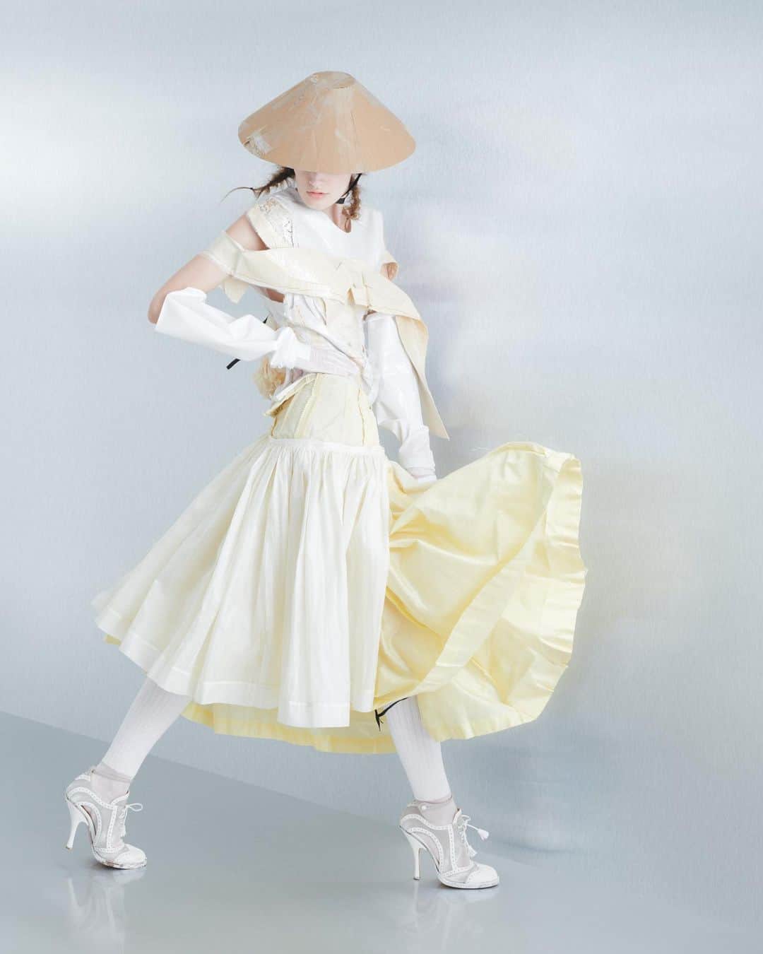 Maison Margielaのインスタグラム：「For the Spring-Summer 2024 Co-Ed Collection, Maison Margiela stages a search for individual truth reflected in the generational adaptation of an inherited wardrobe. Evoking the memory of one age through the radical eyes of the next, Creative Director John Galliano triggers a chemical reaction between eras and attitudes founded in a flashback narrative imagined within the Maison’s ongoing chronicle of the characters Count and Hen.  Look 15. Recicla ivory and ecru poverina t-shirt spliced from an undergarment and a mid-century dress and applied with pressage worn with a Recicla camomile reverse jupon skirt. Cartons conical hat, optical-white dégradé rubberised opera gloves, white silk-cotton knee-high ribbon socks, and white leather and natural linen Tabi bourgeoise spectator pumps. Model @linananananaa_   Look 16. White poverina body spliced from a t-shirt and the lining of a mid-century dress adorned with a black silk pressage bow and worn with an ecru toile exfoliage skirt. Carton conical hat, black dégradé rubberised opera gloves, white silk-cotton knee-high ribbon socks, white leather and natural linen Tabi bourgeoise spectator pumps, and a pied-de-poule-printed canvas shopper with leather Rorschach dotting encased in an ivory tulle illusion carrier bag. Model @sascha._.alexandra   Look 17. Ivory poverino t-shirt spliced from an undergarment and a mid-century cocktail dress worn with dove grey wool-mohair cavalry twill dancing-hem culottes. Clear binliner woven conical hat, mushroom grey leather opera gloves, white silk-cotton knee-high ribbon socks, and black leather and bianchetto linen Tabi monster spectator sling-backs. Model Goy Michael  Look 18. Dark grey resinated pied-de-poule-printed cloche-collar coat with Rorschach dotting worn over black latex briefs. Clear binliner woven conical hat, bianchetto leather opera gloves, white silk-cotton knee-high ribbon socks, black leather and bianchetto Tabi monster sling-backs, and a pied-de-poule-printed canvas bag with Rorschach dotting crafted in the memory of a paper bag encased in an ivory tulle illusion carrier bag. Model @shaom_inghao」
