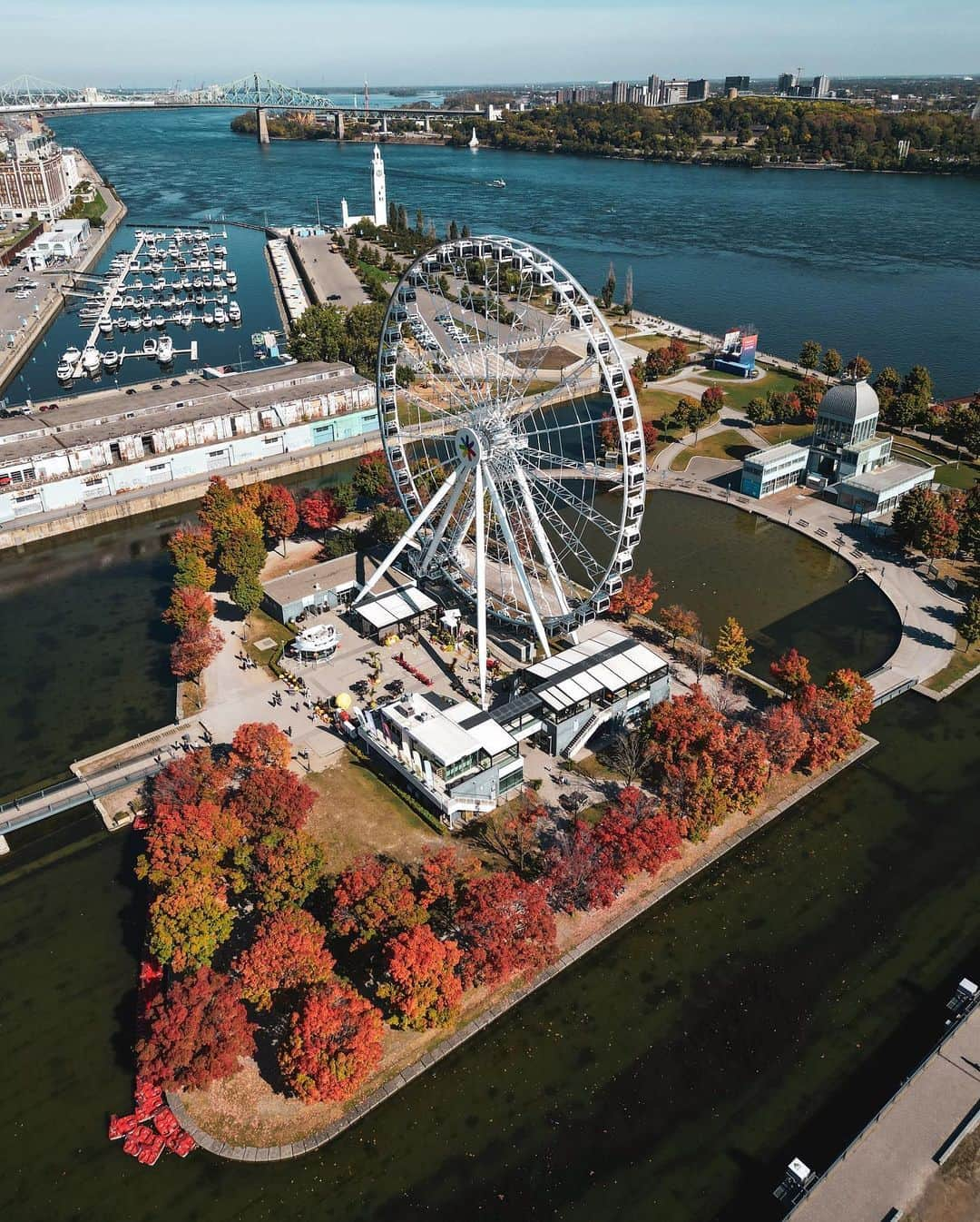 Explore Canadaさんのインスタグラム写真 - (Explore CanadaInstagram)「You spin me right ’round, baby, right ’round 🎵  Located in the Old Port of Montréal, La Grande Roue de Montréal, is Canada’s tallest observation wheel. Open year round, it stands 60 meters (197 feet) above the Old Port, providing 20-minute rotations with sweeping 360-degree views. The perfect place to view the city’s fall colours. 🍂  📷: @jfsavaria 📍 : Old Port of Montréal @tourismequebec @montreal  #BonjourQuebec #ExploreCanada  Image description: An aerial view of an observation wheel surrounded by orange, red and green trees. Docked boats, a bridge and city buildings are seen in the distance.」10月18日 1時30分 - explorecanada