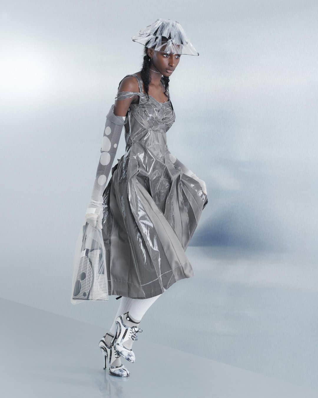 Maison Margielaさんのインスタグラム写真 - (Maison MargielaInstagram)「For the Spring-Summer 2024 Co-Ed Collection, Maison Margiela stages a search for individual truth reflected in the generational adaptation of an inherited wardrobe. Evoking the memory of one age through the radical eyes of the next, Creative Director John Galliano triggers a chemical reaction between eras and attitudes founded in a flashback narrative imagined within the Maison’s ongoing chronicle of the characters Count and Hen.   Look 19. Slate grey viscose decortiqué bustier applied with pressage worn with a black paperised pied-de-poule-printed exfoliage skirt with Rorschach dotting. Carton conical hat, pied-de-poule-printed dégradé organza opera gloves with Rorschach dotting, white silk-cotton knee-high ribbon socks, white leather and natural linen Tabi bourgeoise spectator pumps, and a pied-de-poule-printed canvas fortune cookie bag with leather Rorschach dotting encased in an ivory tulle illusion carrier bag. Model @col_thedoll   Look 20. Mushroom grey lining pressage dress. Clear binliner woven conical hat, pied-de-poule-printed dégradé organza opera gloves with Rorschach dotting, white silk-cotton knee-high ribbon socks, bianchetto leather Tabi bourgeoise spectator pumps, and a pied-de-poule-printed canvas cylinder bag with leather Rorschach dotting encased in an ivory tulle illusion carrier bag. Model Fatou Seck」10月18日 15時05分 - maisonmargiela