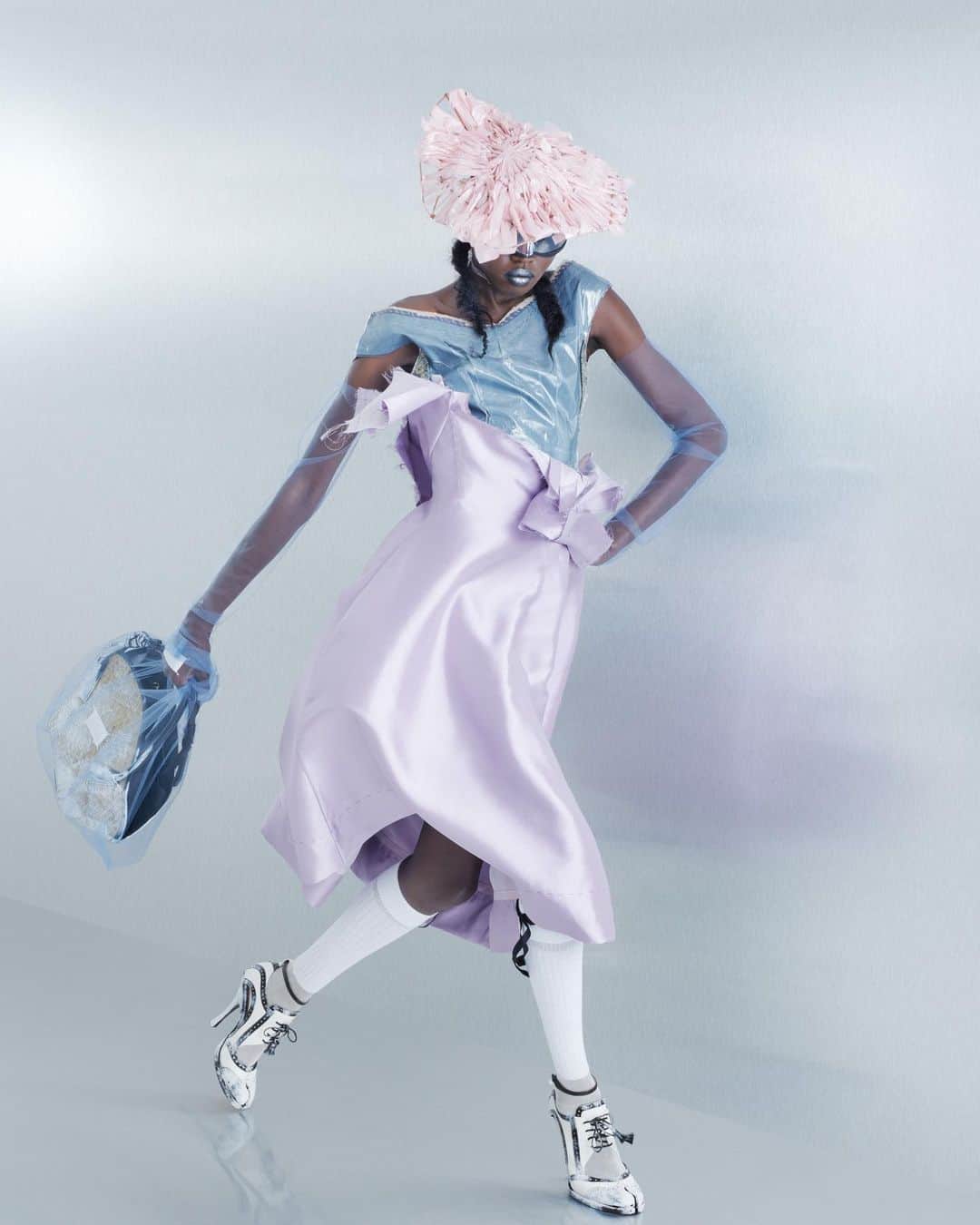 Maison Margielaのインスタグラム：「For the Spring-Summer 2024 Co-Ed Collection, Maison Margiela stages a search for individual truth reflected in the generational adaptation of an inherited wardrobe. Evoking the memory of one age through the radical eyes of the next, Creative Director John Galliano triggers a chemical reaction between eras and attitudes founded in a flashback narrative imagined within the Maison’s ongoing chronicle of the characters Count and Hen.  Look 26. Lilac silk-mikado exfoliage skirt worn over a slate decortiqué bustier applied with pressage. Rose pink binliner headpiece woven in the memory of a mid-century hat, Maison Margiela x Gentle Monster black chrome robotic mask sunglasses, violet tulle illusion opera gloves, white silk-cotton knee-high ribbon socks, bianchetto leather Tabi bourgeoise spectator pumps, and a bianchetto basket-weave fortune cookie bag encased in a violet tulle illusion carrier bag. Model @anyyier   Look 27. A dove grey exfoliage skirt applied with pressage worn over an Eau de Nile silk-taffeta decortiqué romper. Mint binliner headpiece woven in the memory of a mid-century hat, Maison Margiela x Gentle Monster chrome robotic mask sunglasses, sage tulle illusion opera gloves, white silk-cotton knee-high ribbon socks, bianchetto leather Tabi bourgeoise spectator pumps, and a bianchetto basket-weave cylinder bag encased in a sage tulle illusion carrier bag. Model @vilmasj   Look 28. Slate grey exfoliage skirt applied with pressage worn over a Recicla rose taffeta romper. Petrol blue binliner headpiece woven in the memory of a mid-century hat, Maison Margiela x Gentle Monster blue chrome robotic mask sunglasses, slate tulle illusion opera gloves, white silk-cotton knee-high ribbon socks, bianchetto leather Tabi monster sling-backs, and a bianchetto basket-weave cylinder bag encased in a slate tulle illusion carrier bag. Model @tijs_van_der_gun」