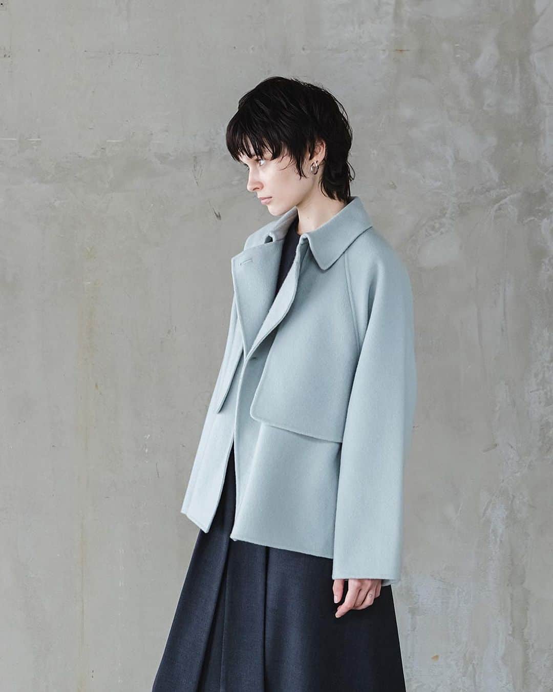 ENCHAINEMENT/mignonのインスタグラム：「.  —Double Faced Wool Short Coat— ブラック/オフホワイト/ライトグリーン No.7033101  ウール100％で暖かさと軽さが特徴のメルトン素材を使用したリバーショートコート。トレンチコートのディテールを取り入れながら、ボタンを留めると表から、ボタンが見えないミニマルなデザインが飽きの来ない1枚。軽く羽織れる丈感で秋口から寒い冬でも長く着用して頂くことが可能。品のあるマスキュリンなコーディネートにもマッチします。ゆとりのあるラグランスリーブで厚手のニットも着込めるデザイン。  #enchainement #アンシェヌマン #アトレ恵比寿 #新丸の内ビル #なんばパークス #広島パセーラ #アミュプラザ博多」