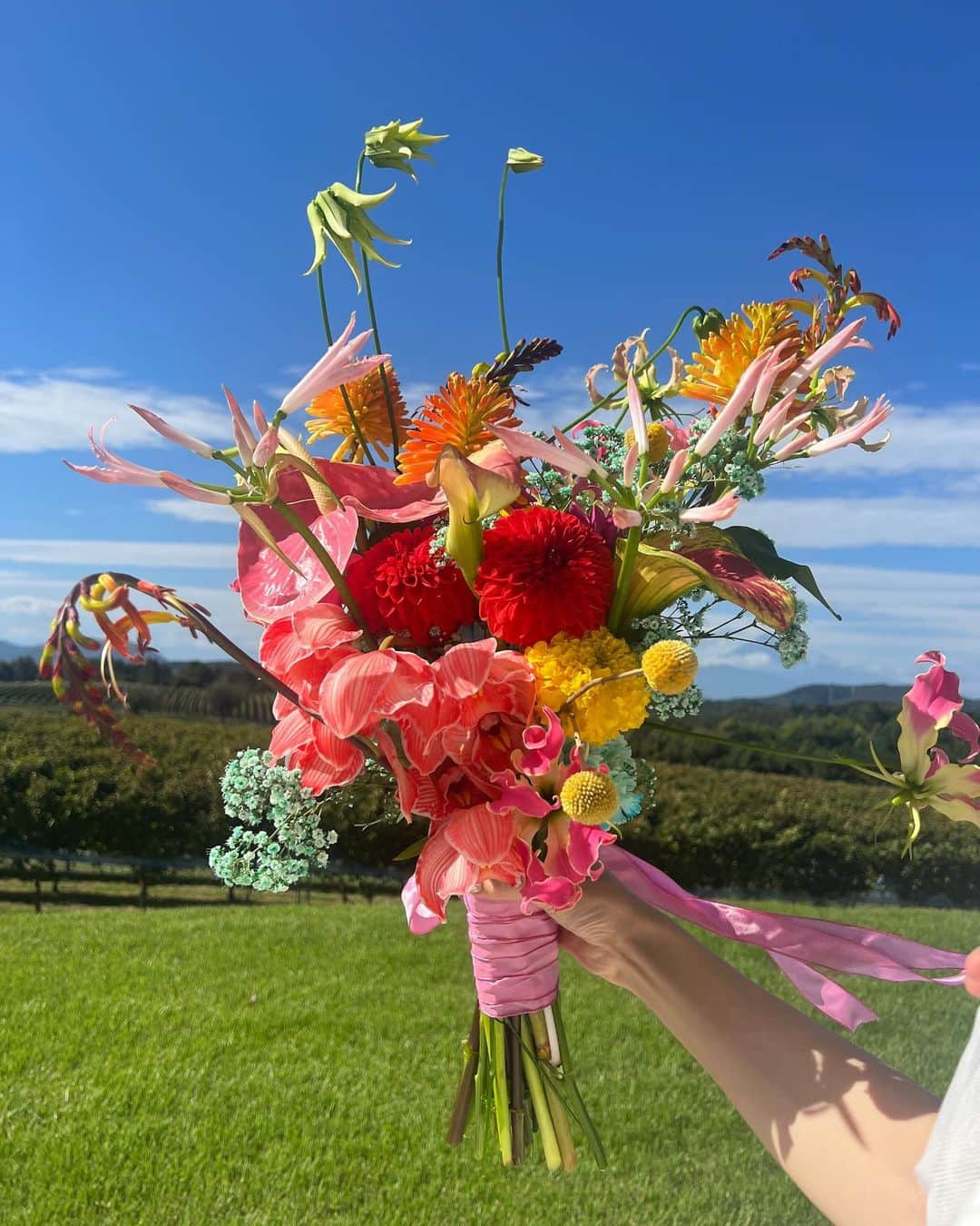 あさぎーにょのインスタグラム：「ウェディングブーケ💐🕊️ドレスやアクセサリーと同じくらい大切な存在！ なんとも美しい最高のブーケが…  特に最後のフィナーレブーケは 暗い夜にも鮮やかに映えて 個性的なドレスとベストマッチング😭✨  逆に挙式は落ち着いた感じで 艶めいたアンスリュームに 雫のようなパールがころりころころと♡ きゃんきゃん可愛い〜！  うさぎドレスはやっぱりオレンジ🥕 ってことでオレンジの薔薇を。  どれも色味のあるポップなブーケだけれど ドレスやムードに合わせて 全然違う雰囲気に仕上げてもらいました💐💐💐 （リボンも選ばせてもらったけどとっても印象変わって楽しいよ！）  そして絶対おすすめなのは 新郎の胸ポケットに入れるブートニア！！ これあって良かった😭✨🤍 メンズってドレスほど大きくドレスチェンジできないけれど ブートニアがあることで 印象も変わるし新郎新婦のリンク感もあって◎  絶対あった方がいい！！！ プレ花嫁さんにおすすめ！  お願いしたのは仲良くさせて頂いてる てん.のなおさん♡ @naoten10  天才的で最高すぎるー！！！  お花って人を何倍も素敵に魅せてくれる魔法だよね 今回の結婚式は沢山お花に助けられたなー💐✨  そろそろウェディング投稿は終盤です！ （まだあるんかいって？笑）  bouquet @naoten10  #ウェディング#プレ花嫁#ウエディング#結婚式#ブーケ#ウェディングブーケ #ウエディングブーケ#ウェディングドレス」