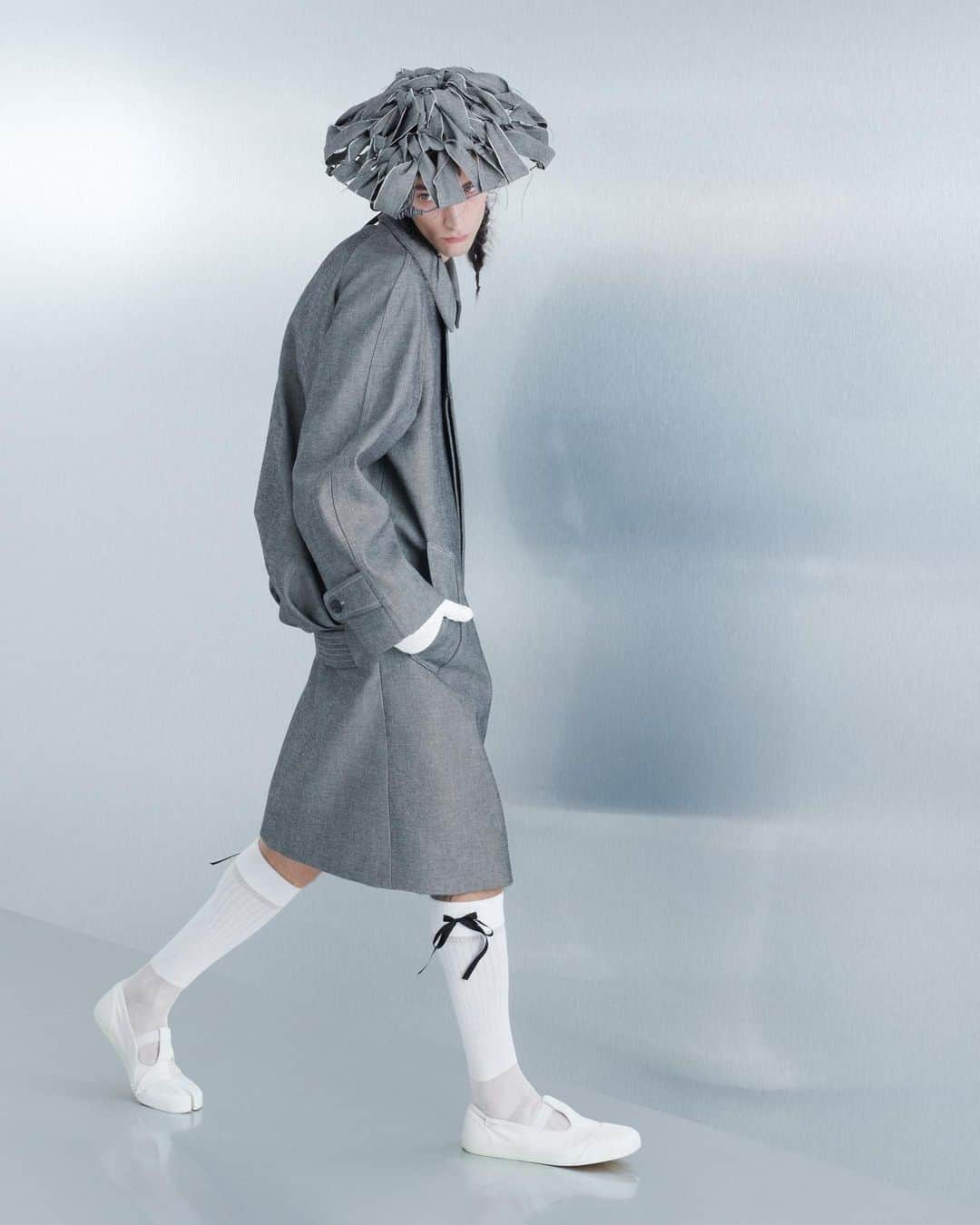 Maison Margielaのインスタグラム：「For the Spring-Summer 2024 Co-Ed Collection, Maison Margiela stages a search for individual truth reflected in the generational adaptation of an inherited wardrobe. Evoking the memory of one age through the radical eyes of the next, Creative Director John Galliano triggers a chemical reaction between eras and attitudes founded in a flashback narrative imagined within the Maison’s ongoing chronicle of the characters Count and Hen.  Look 32. Caviar Oxford-weave cotton beetle-back car coat worn over black latex briefs. Caviar Oxford-weave cotton conical hat, white lambskin gentleman’s gloves, white silk-cotton knee-high ribbon socks, and bianchetto canvas Tabi deck shoes. Model @thomas_riguelle   Look 34. Black canvas coat cut in the memory of the classic ladies’ wardrobe worn over black latex briefs. Black canvas woven conical hat, white lambskin gentleman’s gloves, white silk-cotton knee-high ribbon socks, and bianchetto canvas Tabi deck shoes. Model Adrians Smats」