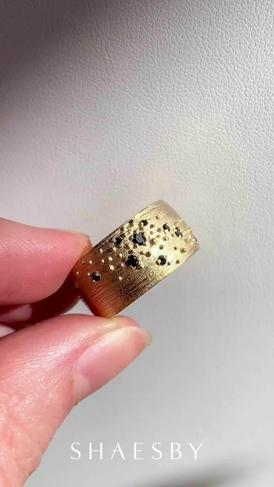 シェイスビーのインスタグラム：「Our 14k Wide Isla Band resembles the constellations in the night sky 🌌 This ring is hand cast in our Austin studio and has a distinct constellation of black diamonds and polished gold beads.」