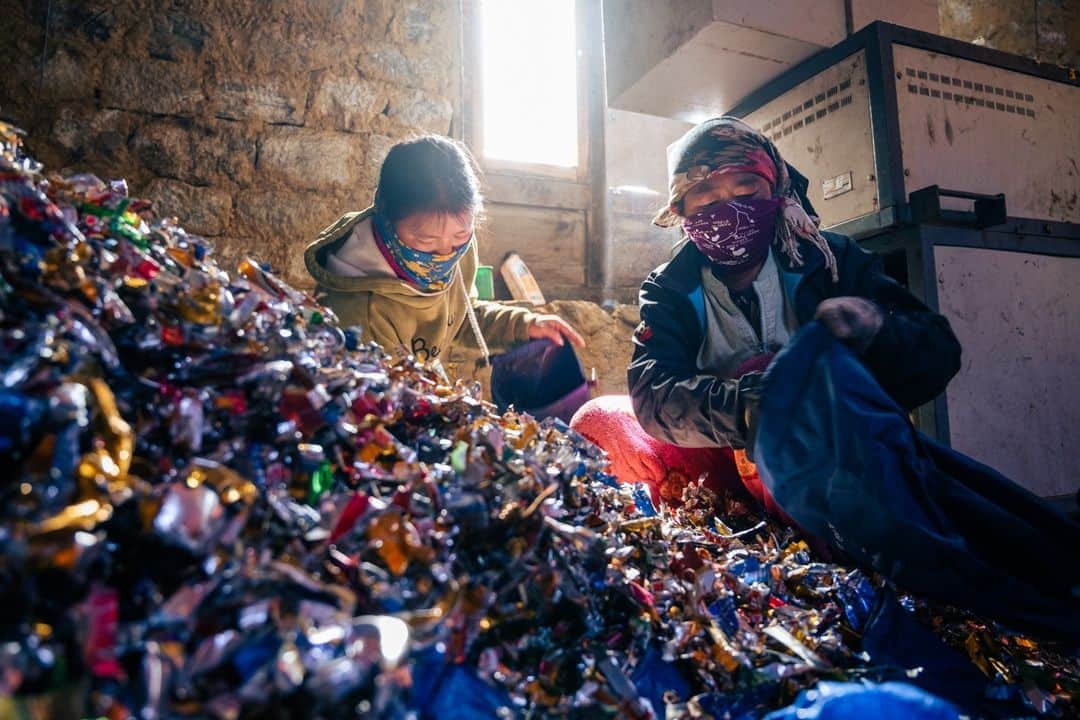 ナショナルジオグラフィックのインスタグラム：「Photos by @martinedstrom | Two women pack dry bags full of shredded metal and plastic, to be brought down from the Mount Everest region in Nepal for recycling in the capital, Kathmandu. Every year, up to 60,000 tourists visit Sagarmatha National Park to see Everest—and leave a lot of trash behind in the mountains. Local waste infrastructure can't cope with the amount of litter and refuse. So local NGOs Sagarmatha Pollution Control Committee and Sagarmatha Next are spearheading a solution to crowdsource the recycling process, offering tourists a chance to carry down shredded waste as they leave the national park area beneath Mount Everest. So far, more than 10 metric tons of shredded waste has been brought down for recycling. Follow @martinedstrom for more on the story.」