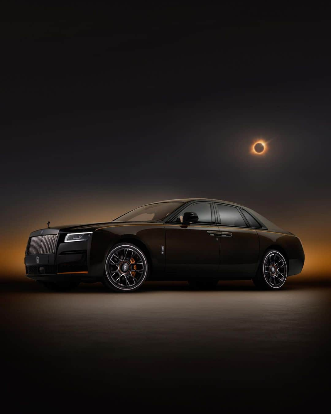 ロールス・ロイスのインスタグラム：「An entrancing Private Collection car, #BlackBadge Ghost Ékleipsis immortalises the seldom-seen wonder of a solar eclipse.   The dark exterior colour, Lyrical Copper, is enriched with powdered copper pigment. In light, the pigment reveals a dramatic iridescence, capturing the ethereal light cast by an eclipse.   Discover more; link in bio.   #BespokeIsRollsRoyce  – WLTP (combined): CO2 emissions: 359 g/km; Fuel consumption: 17.9 mpg / 15.8 l/100km.Further information: https://www.rolls-roycemotorcars.com/en_GB/information/fb-dat-wltp.html」