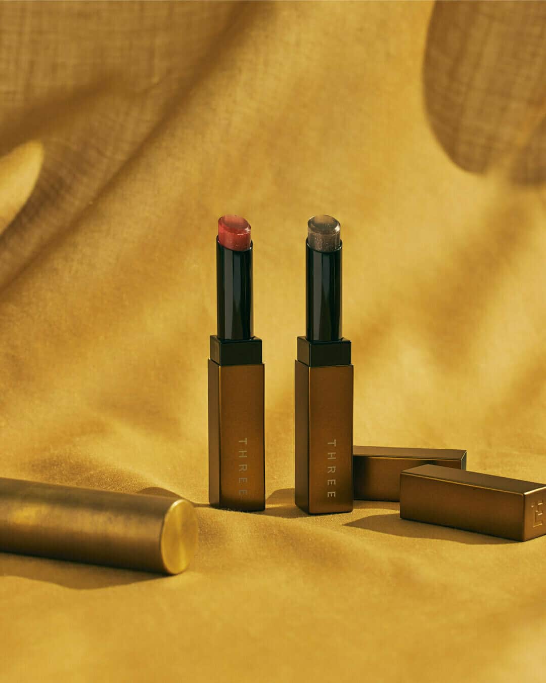 THREEのインスタグラム：「唇にシアーなツヤと血色感。軽やかで繊細な輝きを忍ばせたティントリップ。  THREE ルヴァントリップケアティント K【限定】 全2色 各3,960円（税込）  人気のティントリップに、微細なパールを忍ばせたホリデー限定のカラーが登場。 薄膜の濡れたようなツヤを纏うことができ、ナチュラルな血色感を叶えるレッドと唇の赤みをシックに引き立てるグレーの2色。 8種の植物オイルを配合するなど、乾燥や唇荒れを防ぐ処方で、その人らしいヘルシーな表情に仕上がります。  ーーー 【スワイプしてスウォッチをチェック！】 X01 LIFE SENSE（二枚目） じわっとした血色感とグロウなツヤを効かせた、クリアーレッド。  X02 BEAUTY SENSE（三枚目） 唇本来の赤みをそっと引き出す、ナチュラルなクリアーグレー。  ーーー 【発売日】 ご予約受付中 全国発売：2023年10月25日（水）  #threecosmetics #Three2023HolidayMakeupCollection #ホリデーコレクション」