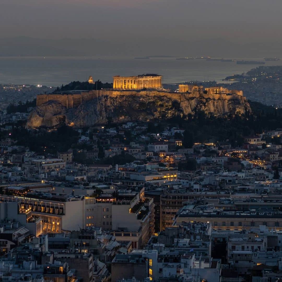 ナショナルジオグラフィックのインスタグラム：「Photo by Muhammed Muheisen @mmuheisen | The fifth-century B.C. Parthenon temple is illuminated atop the ancient Acropolis, with the Saronic Gulf seen in the background, in Athens. For more photos and videos from different parts of the world, follow me @mmuheisen.」