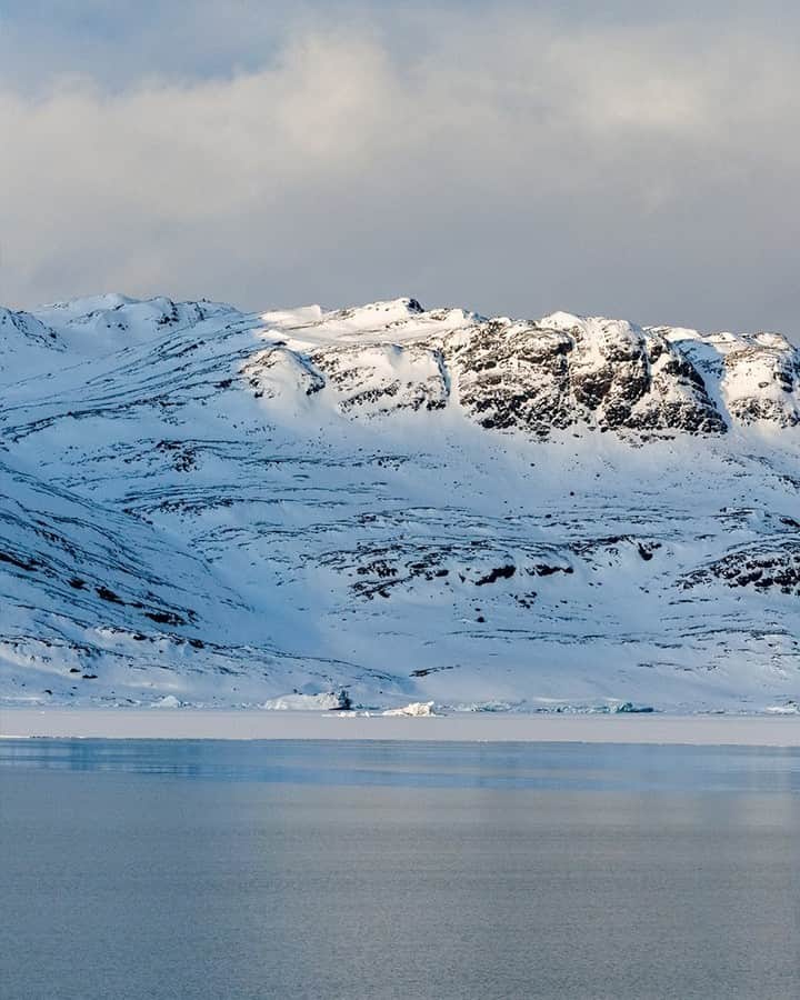 National Geographic Travelのインスタグラム：「Photo by @martinedstrom | Swipe to see the full panorama from Svalbard, Norway. Traveling through the Arctic beneath the midnight sun is a meditative experience. The sun never sets, so you sleep less and have golden light throughout the entire day. But the weather changes quickly, as seen here, when a thick, deep-blue storm rolled in from the west.   Follow @martinedstrom for more travel images from the Nordics.」