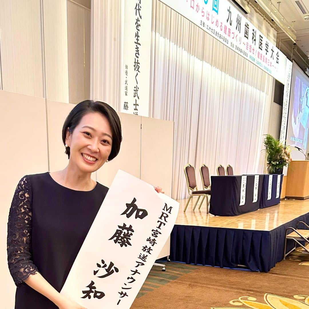 加藤沙知のインスタグラム：「週末の司会のお仕事🎤  登壇者の皆様の机の前に貼られる名前が書かれた紙(前垂れ・名前札などとも呼ばれます)を、ご覧になったことありますか？  司会者の前垂れってあまり無いのですが、 なんと今回、私にも作ってくださっていて、 嬉し恥ずかしでした🥹  司会席前に貼るのは恥ずかしかったので、 遠慮したのですが…笑  開式の前に、嬉しさあまって記念写真を🤭  ありがとうございました🙇‍♀️  #司会#アナウンサー#感謝 #九州歯科医学大会 #今週は宮崎県人会世界大会の司会をさせて頂きます🎤 #沢山の方にお会いできることを楽しみに」