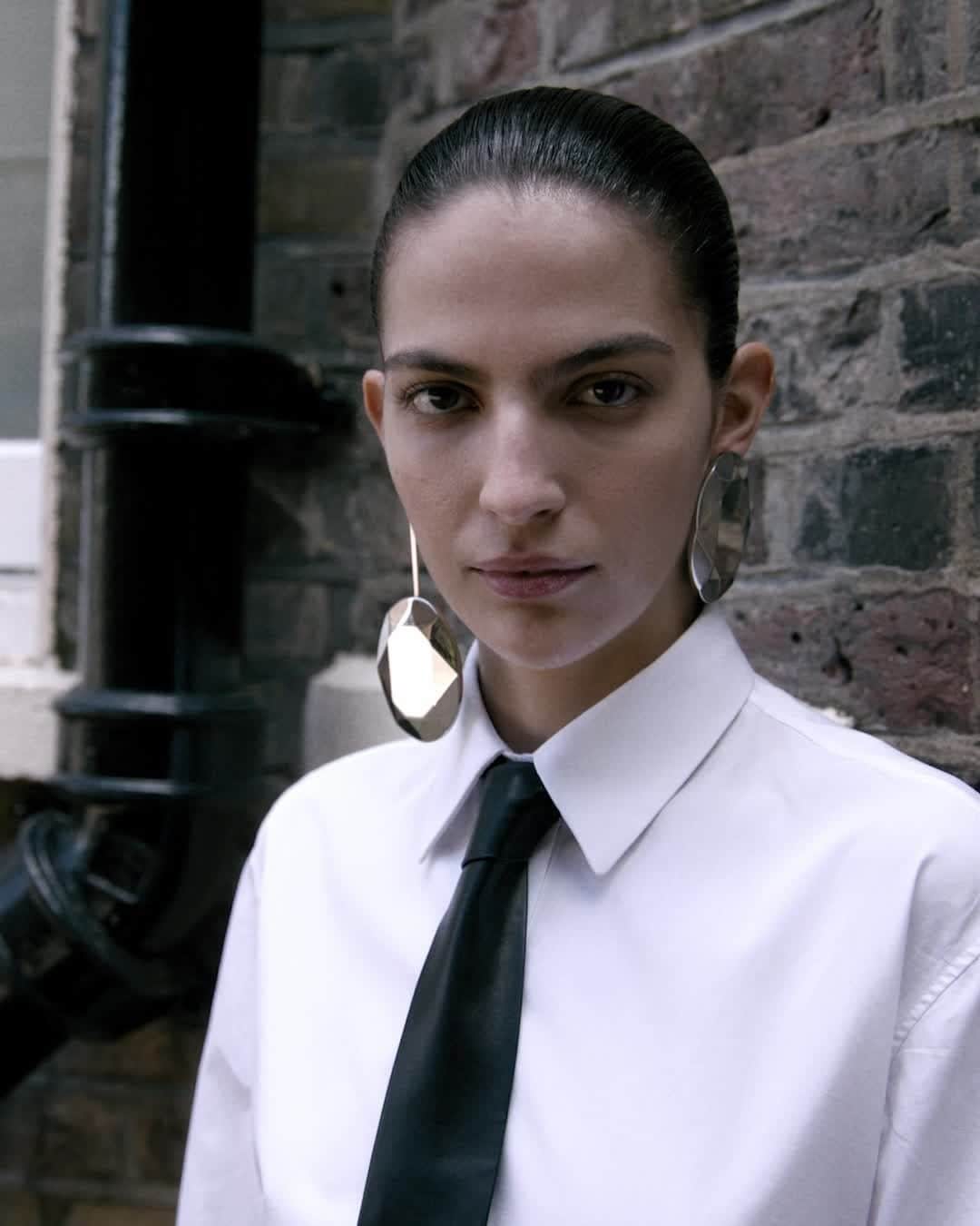 アレキサンダー・マックイーンのインスタグラム：「A white cotton poplin shirt, a tie and an upside down slashed skirt in black with the #McQueenPeak bag and Punk Buckle sandals in red. ⁣ ⁣ Discover the #McQueenAW23 collection via the link in bio.⁣ ⁣ Photographed by @Jet.Swan⁣ Video by @EbbaHult⁣ Track: Neurons by @roblewiscomposer⁣ Music Director: John Gosling」