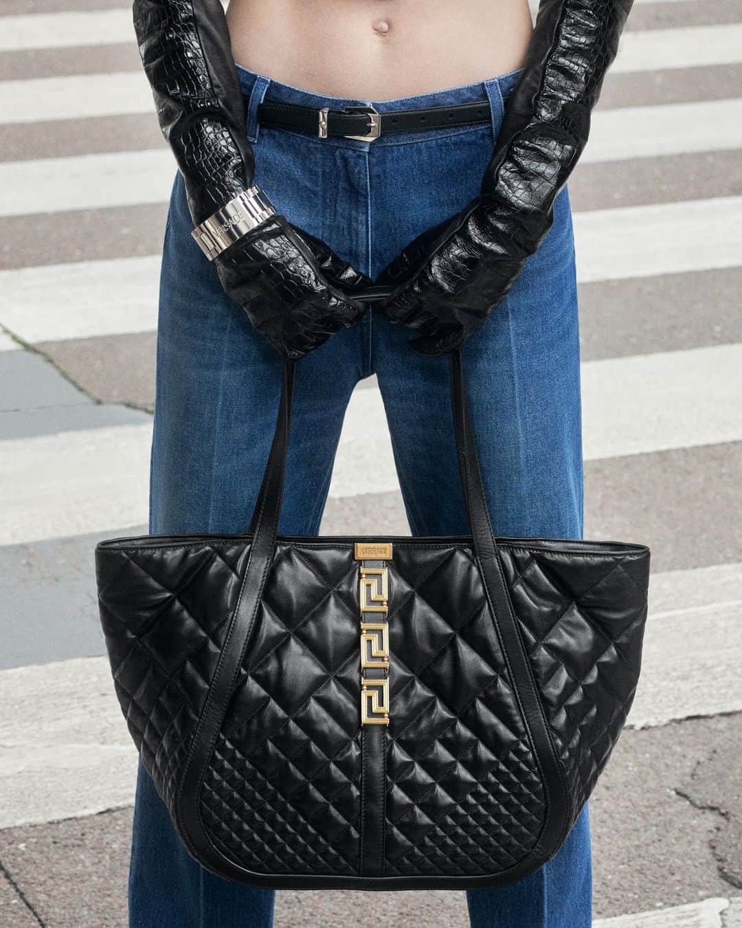 ジャンニヴェルサーチのインスタグラム：「Soft quilted leather in a repeating Versace 'V' motif on the #VersaceGrecaGoddess tote bag.  Model wears tailored denim pants; Greca Goddess tote bag  Photography by Ilya Lipkin  #VersaceFW23 #Versace」